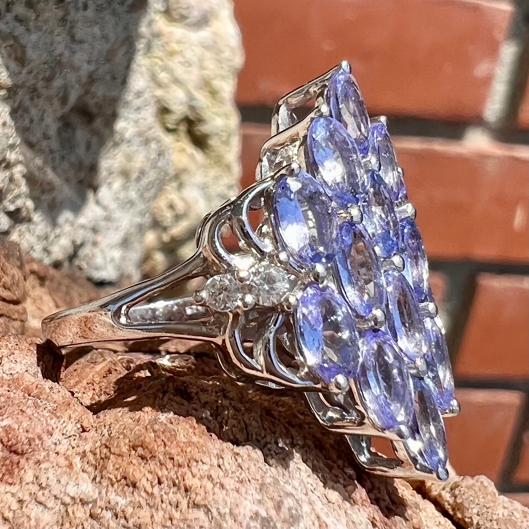 A sterling silver gemstone cluster ring set with oval cut tanzanite stones and round cubic zirconia accents.