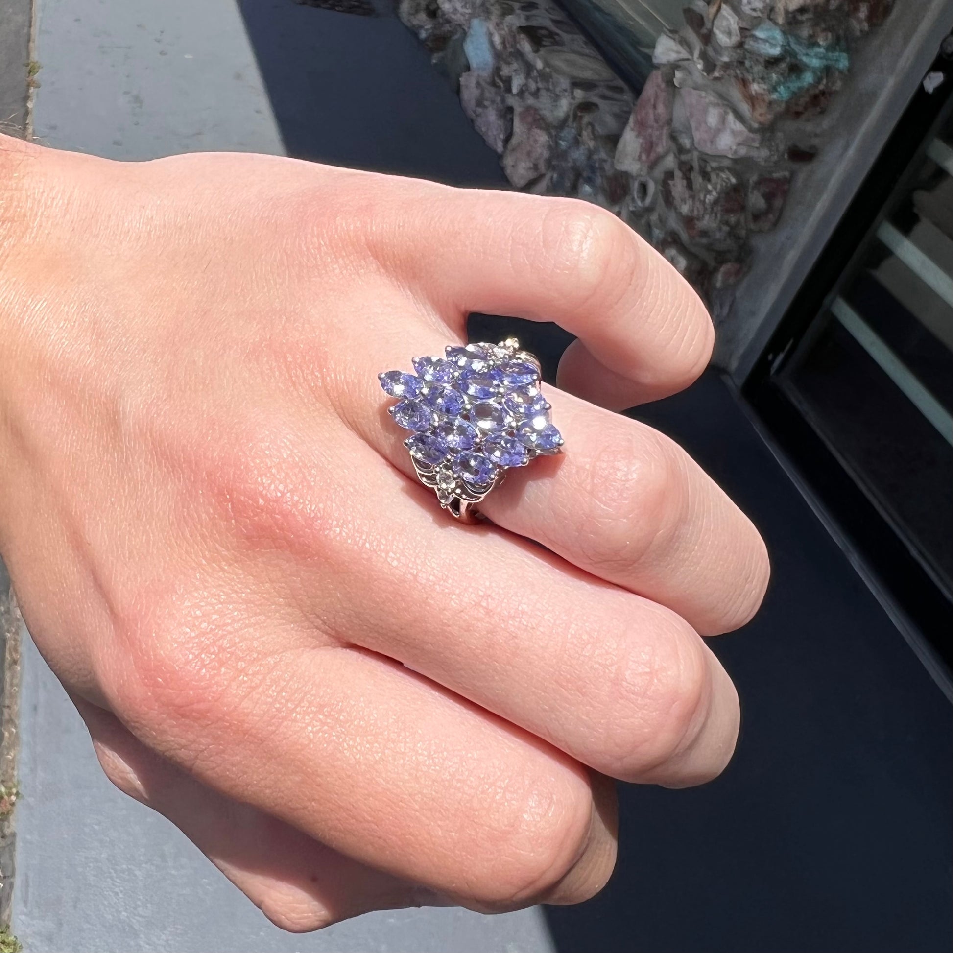 A sterling silver gemstone cluster ring set with oval cut tanzanite stones and round cubic zirconia accents.