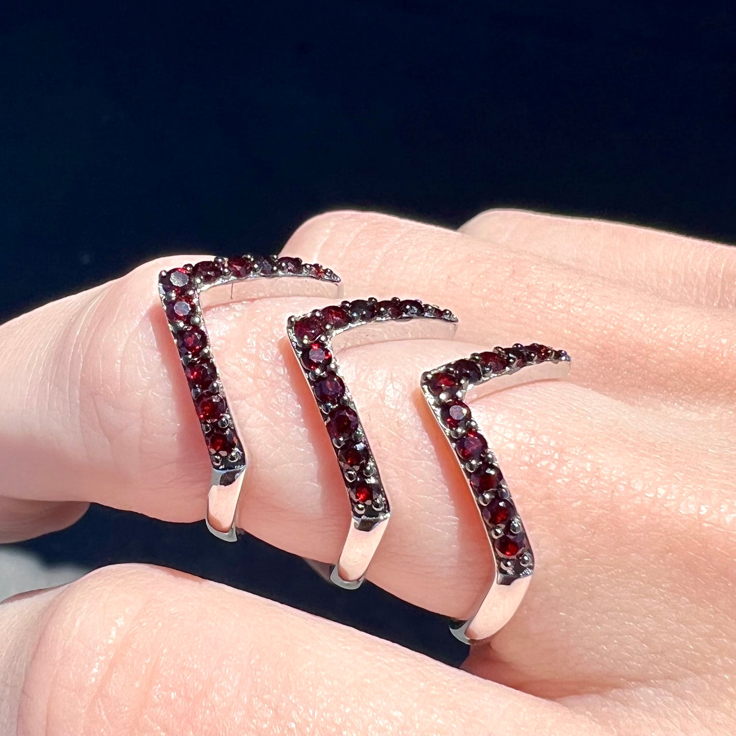 A sterling silver ring pave set with round almandine garnet stones. The piece appears to be three rings in one.