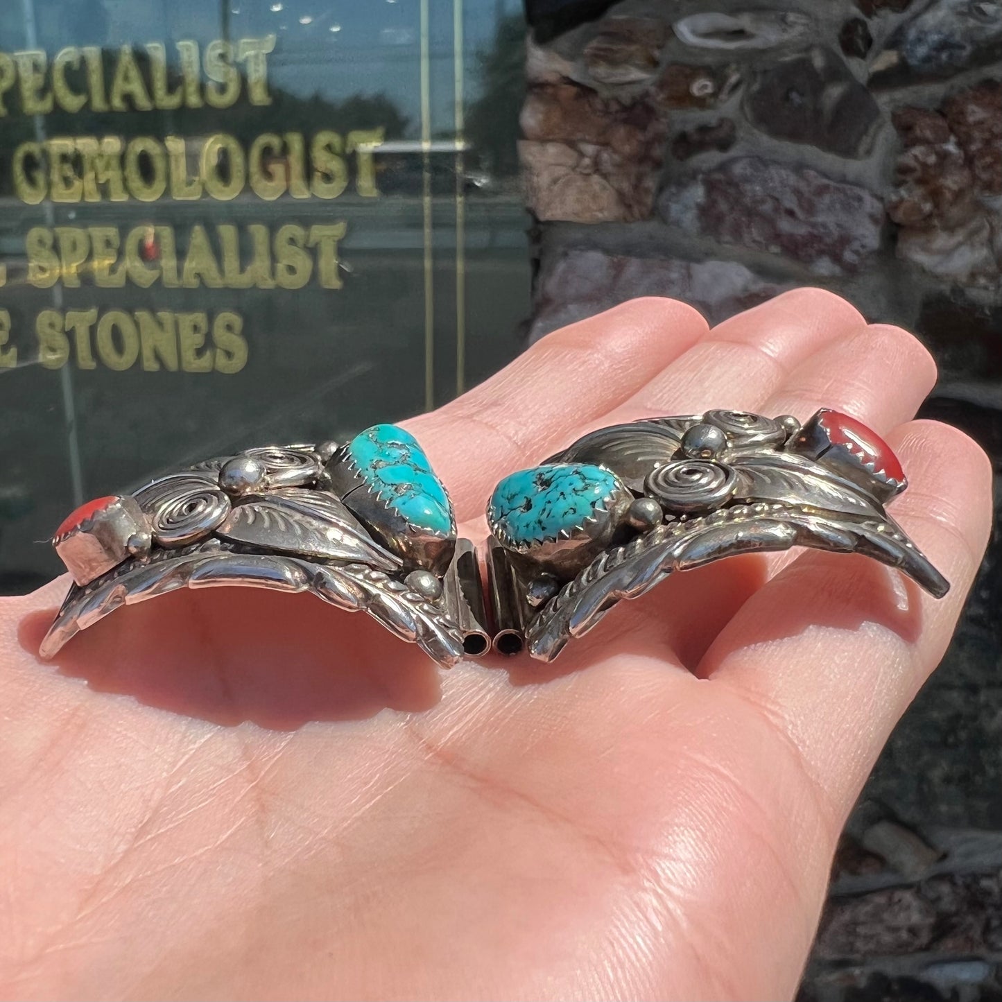 A pair of sterling silver watch cuffs set with turquoise and coral stones.