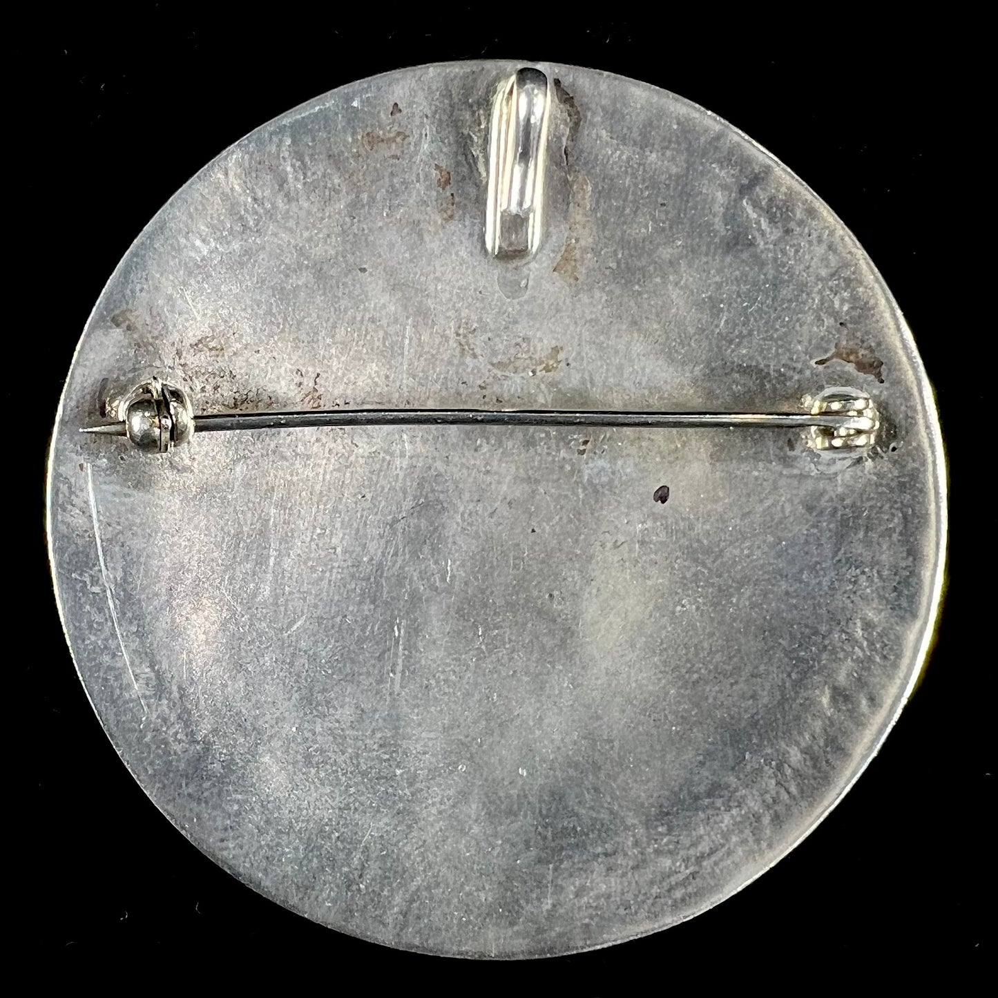 A silver pendant of two flying cranes and two roadrunners inlaid with turquoise, coral, and mother of pearl.