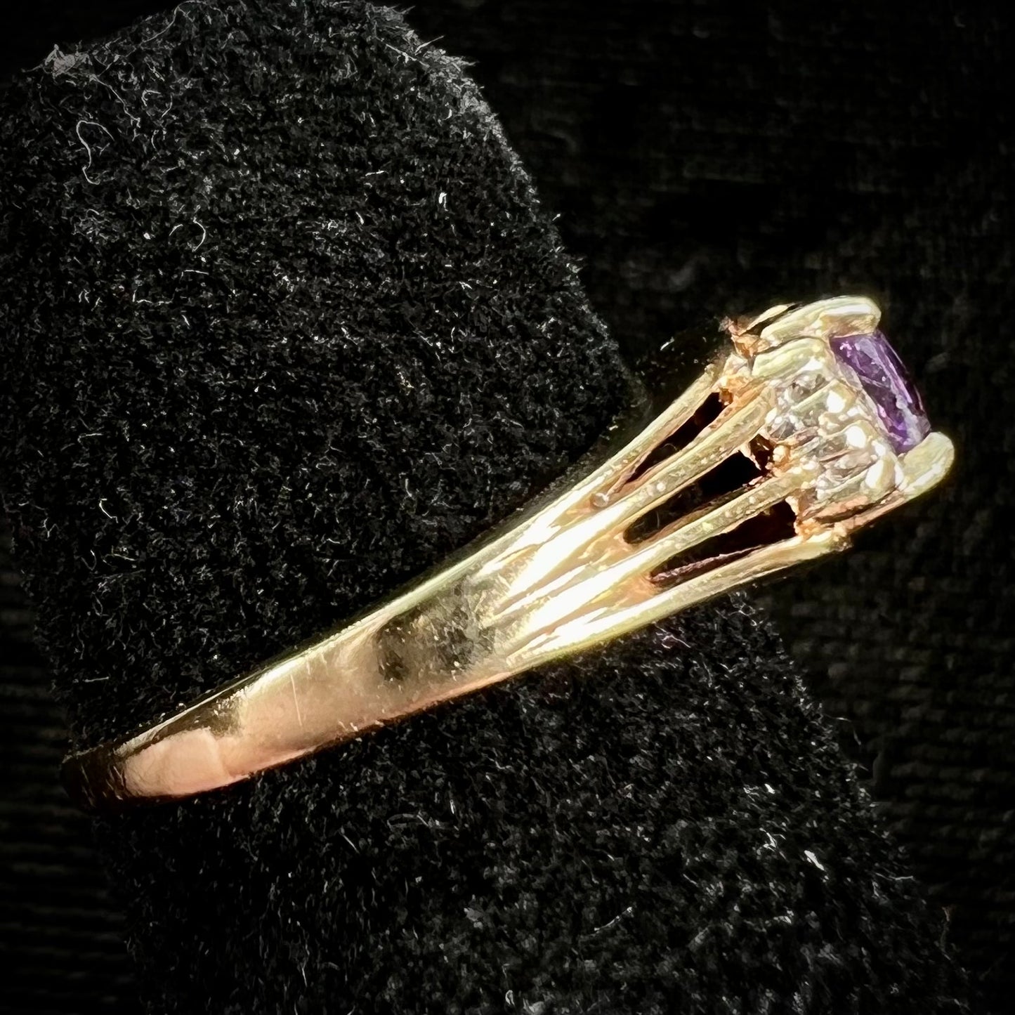 A ladies split shank gold ring set with an oval cut amethyst and round brilliant diamond accents.