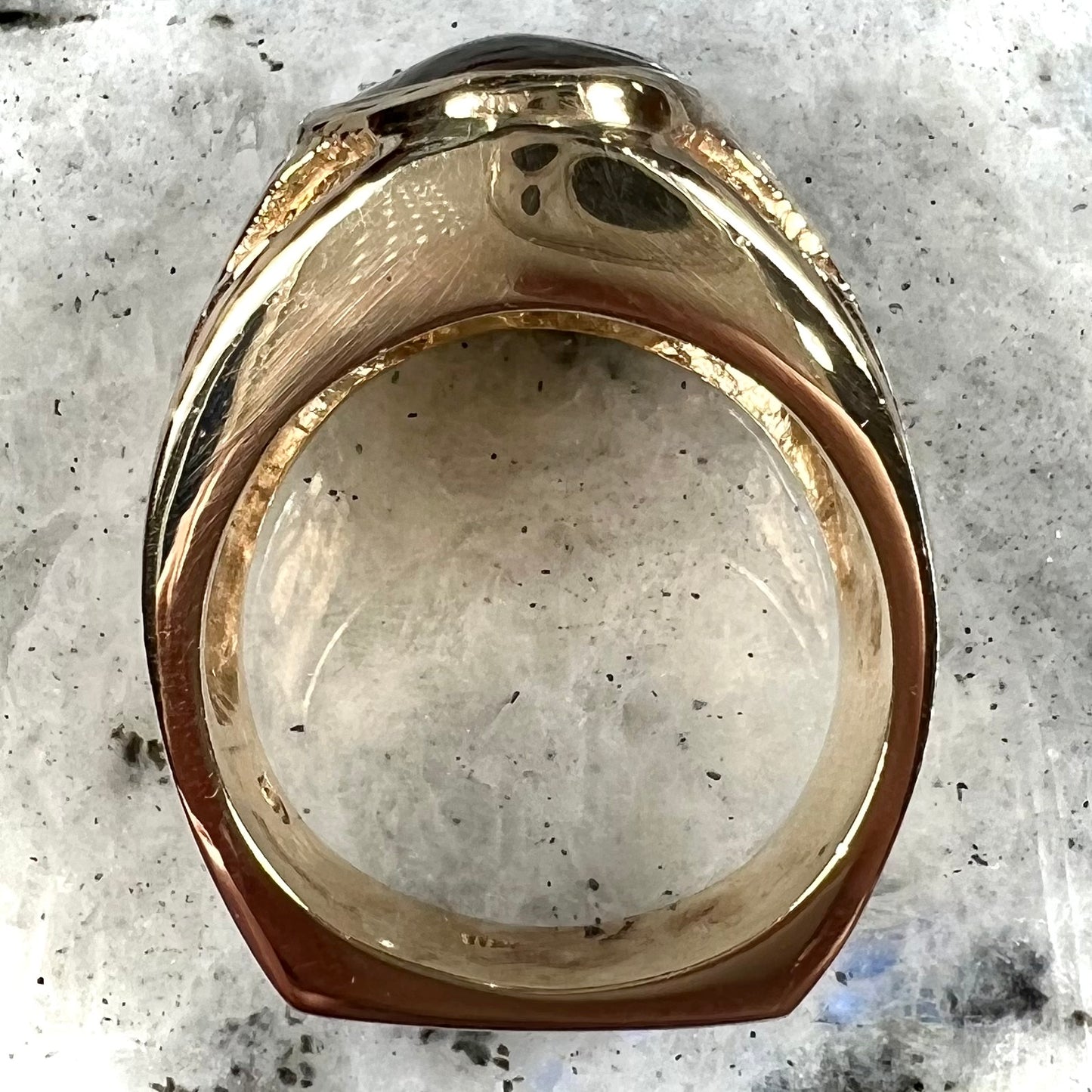 A solid, yellow gold men's fire agate ring. The predominant color is red with green undertones.