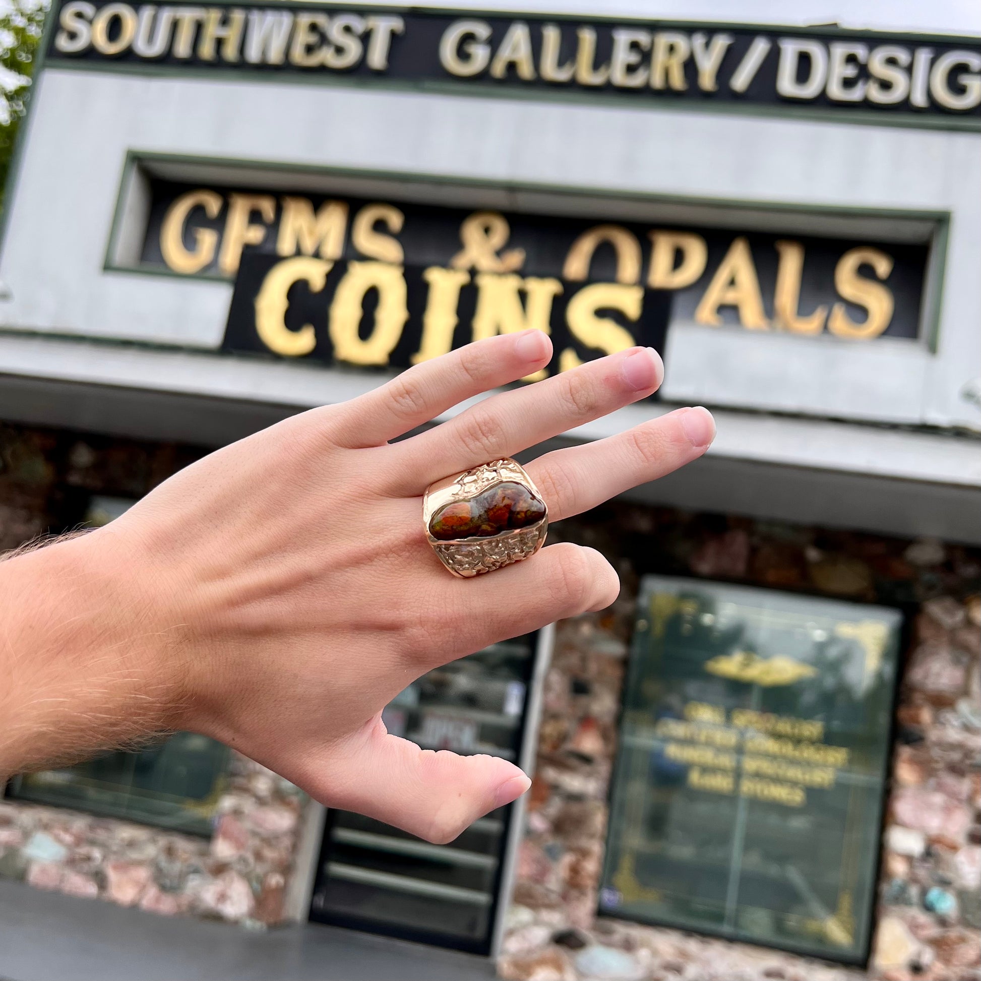 A large nugget style men's fire agate ring cast in yellow gold.  The fire agate is predominantly orange and green.