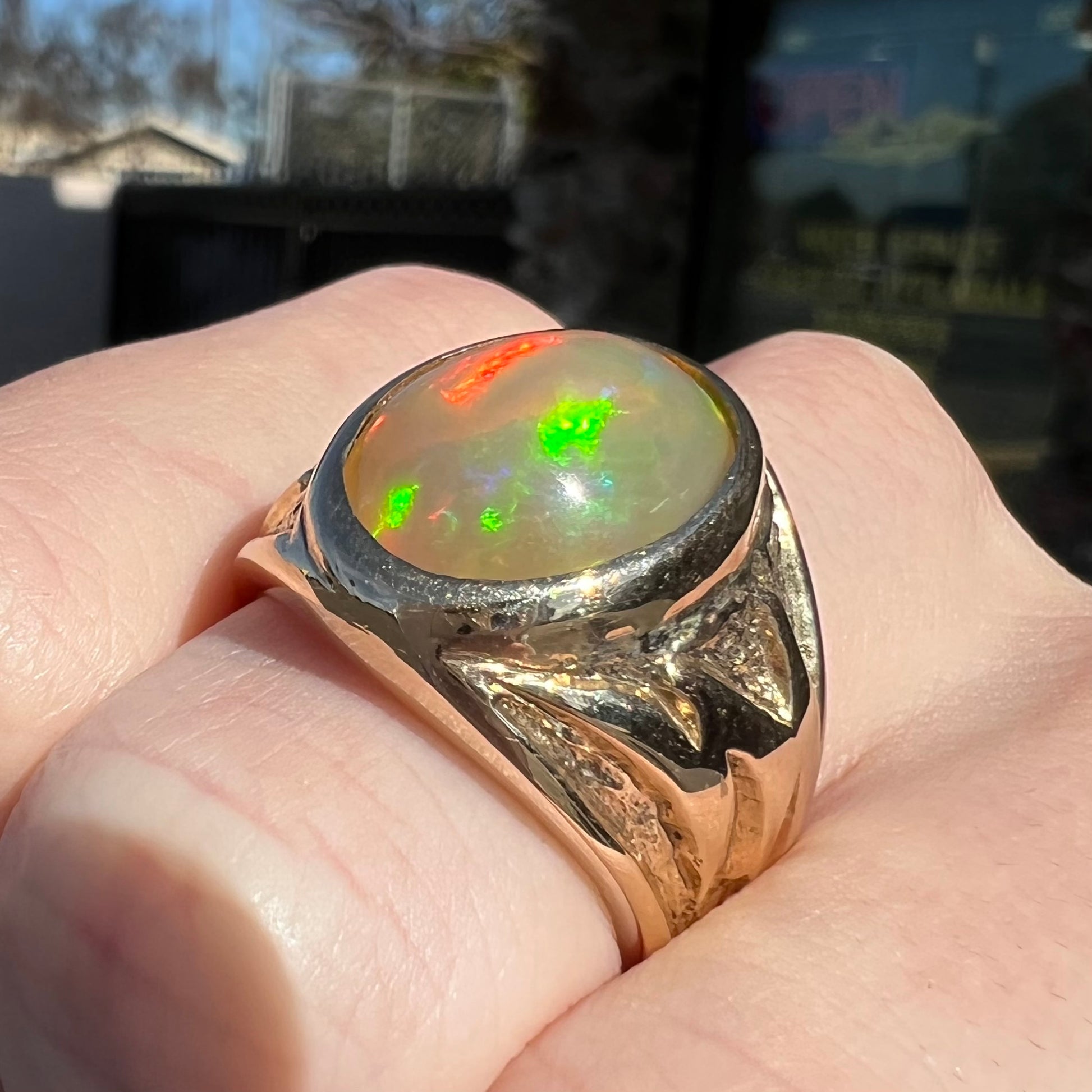 A solid yellow gold solitaire men's fire opal ring.  The stone is an orange oval cabochon cut.