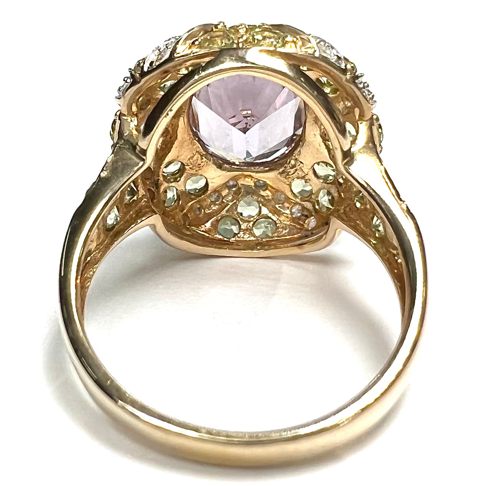 A ladies' yellow gold ring set with an oval cut lavender spinel center stone and diamond and peridot accent stones.