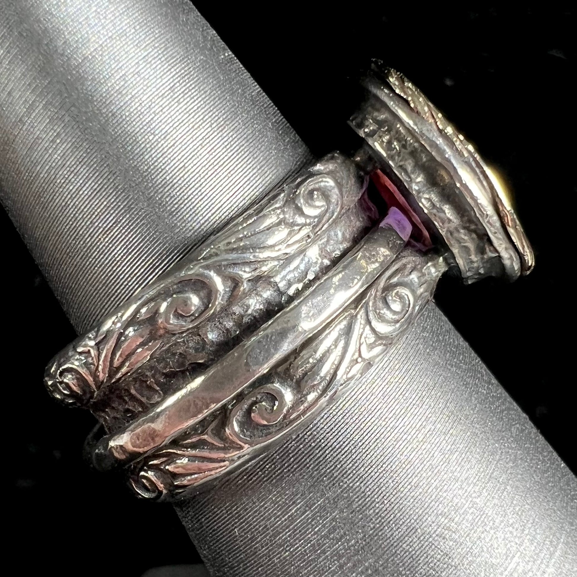 A filigree etched two tone silver and gold spinner ring set with a lab created black opal.