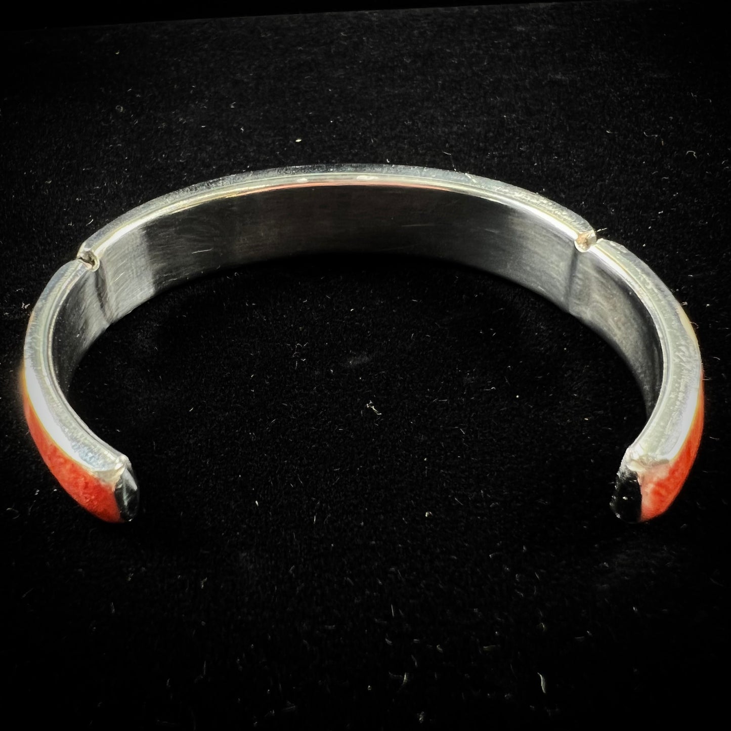 An adjustable stainless steel cuff bracelet inlaid with polished spiny oyster shell.