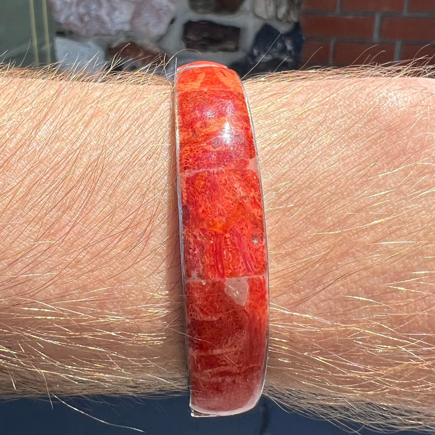 An adjustable stainless steel cuff bracelet inlaid with polished spiny oyster shell.