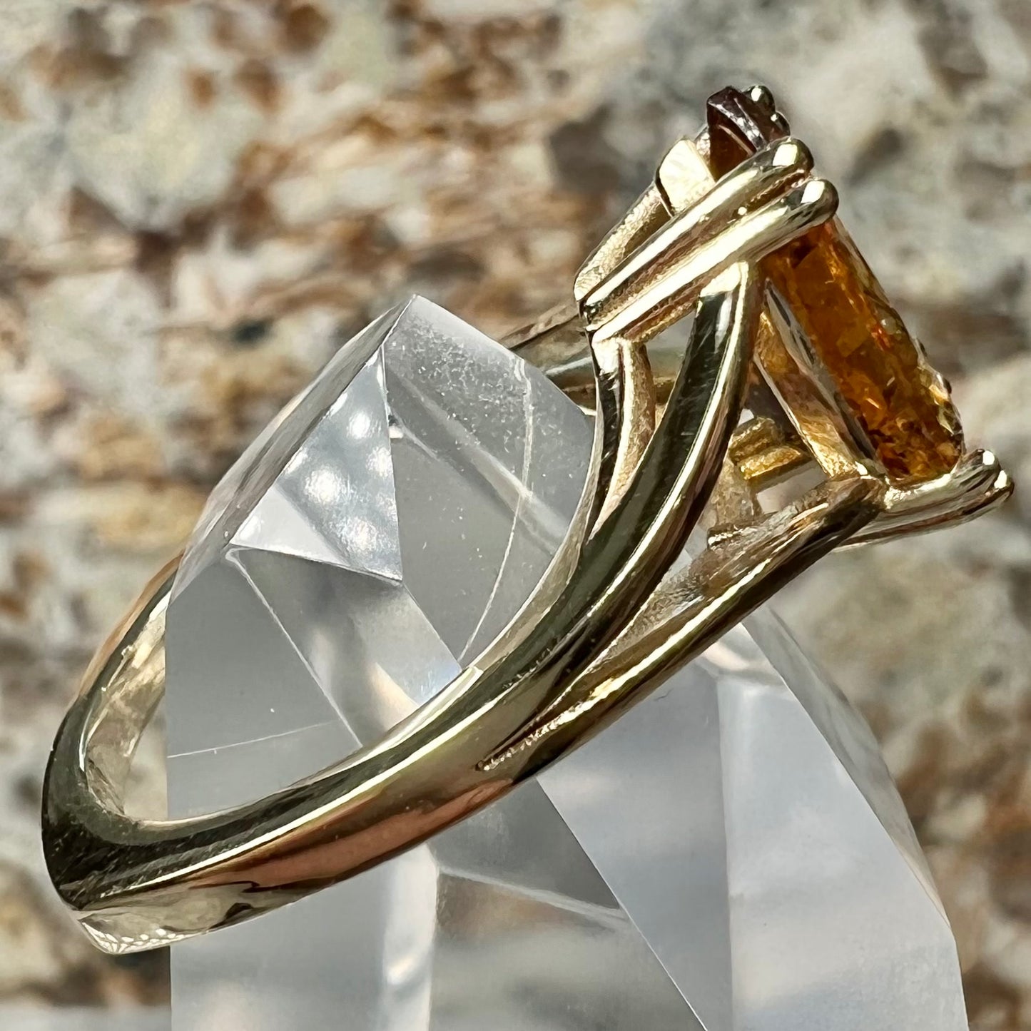 A gold split Euro shank solitaire ring set with an orange pear shape hessonite garnet stone.