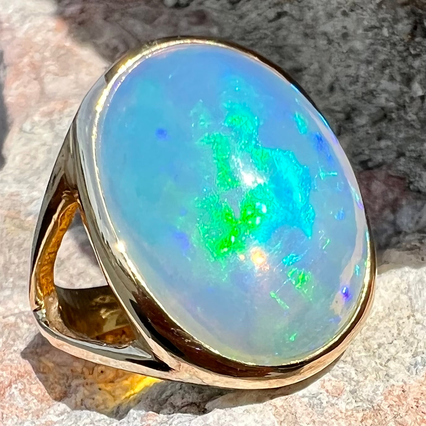 A gold split shank solitaire ring set with an oval cabochon cut 16.83 carat Ethiopian jelly fire opal.