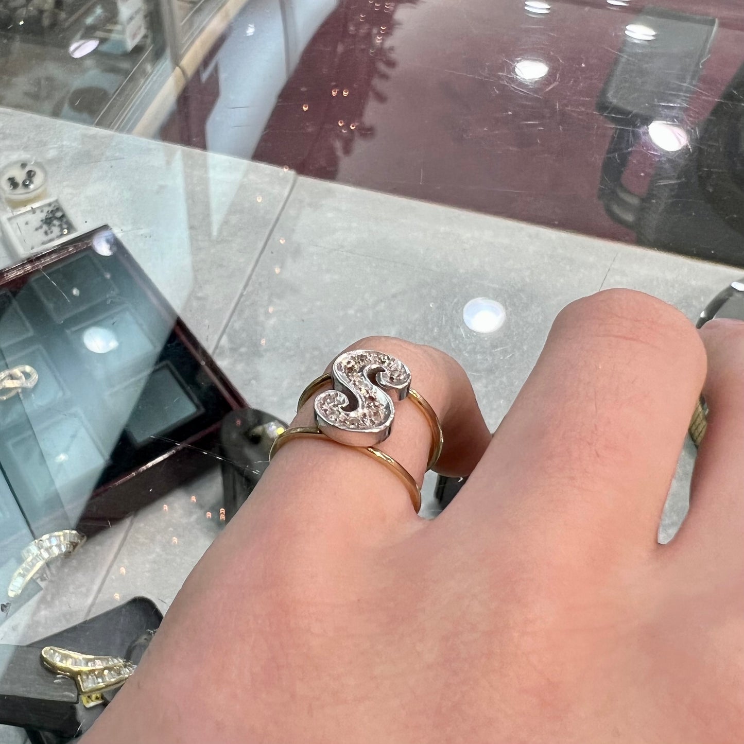 A two tone white and yellow gold initial ring of the letter "S" set with diamonds.