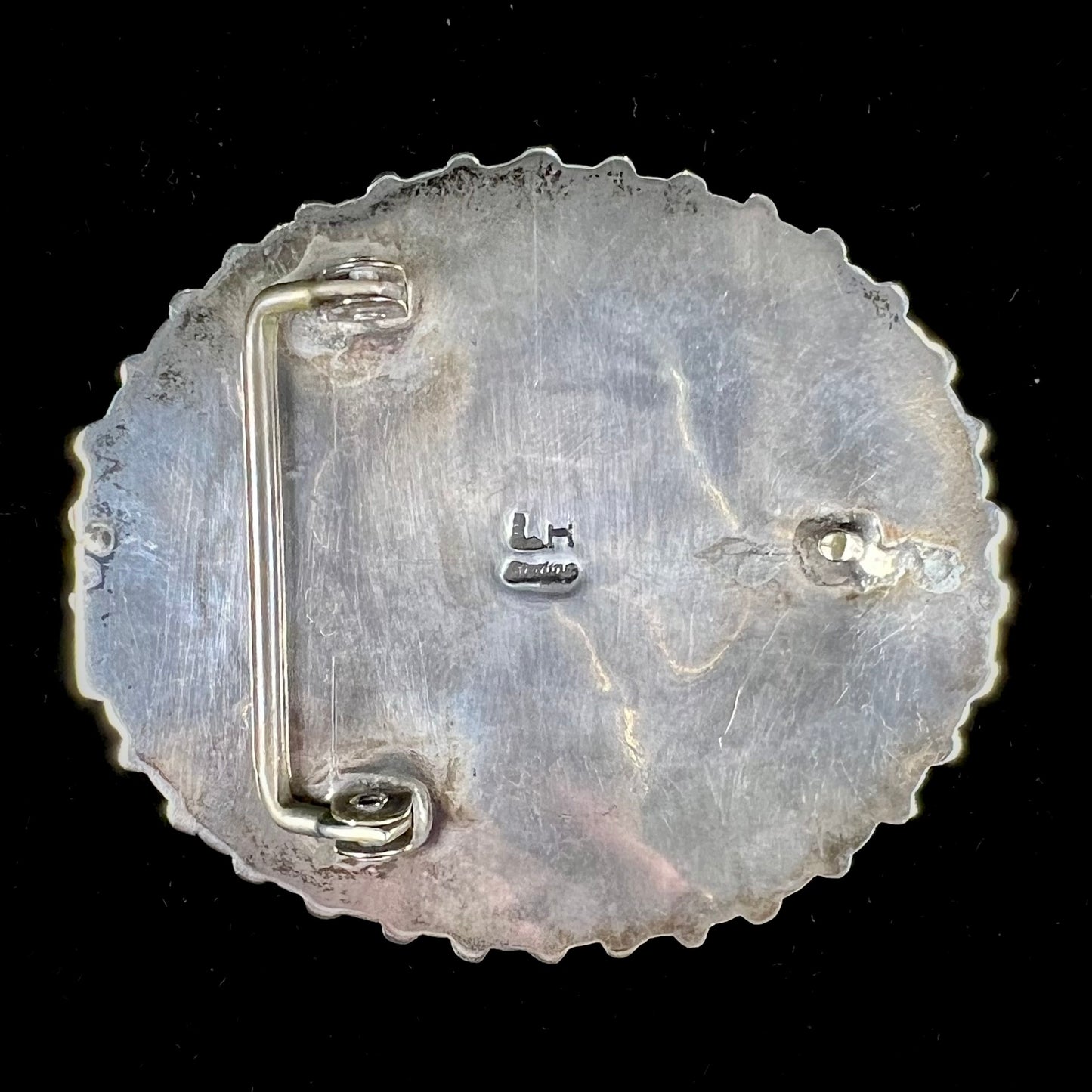 A unisex sterling silver belt buckle featuring the motif of a stone inlaid hummingbird set with petit point turquoise accents, handmade by Navajo artist, Leo G. Harvey.