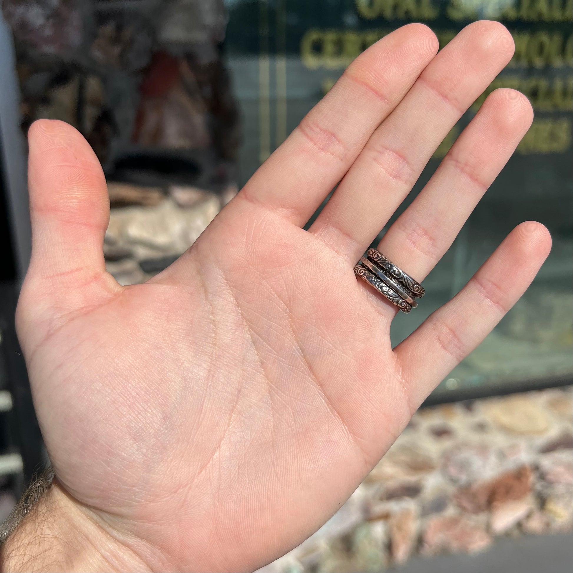 A filigree etched two tone silver and gold spinner ring set with a lab created black opal.