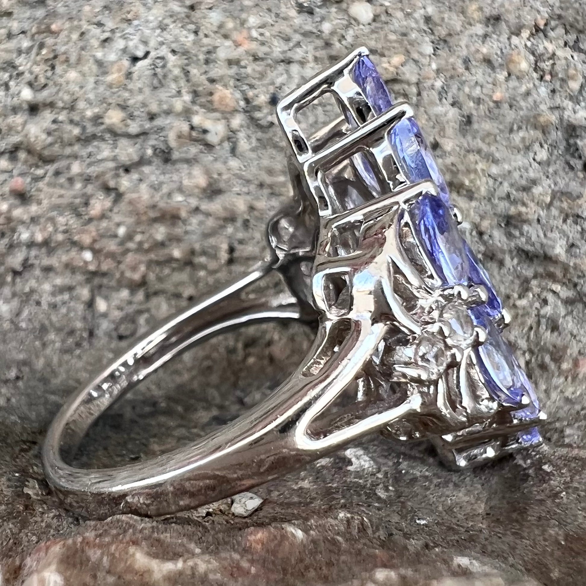 A sterling silver gemstone cluster ring set with oval cut tanzanite stones and round cubic zirconia accents.