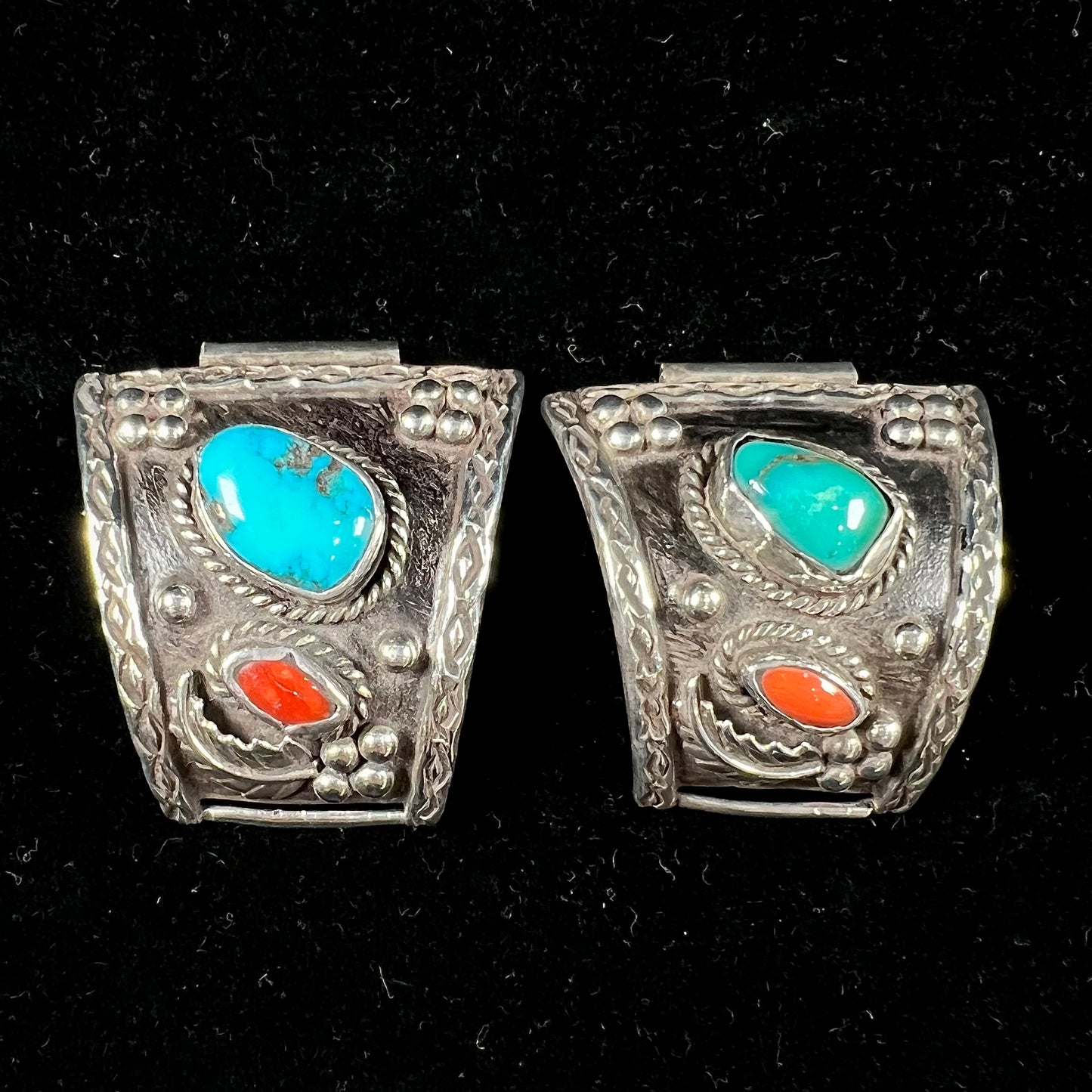 A pair of Navajo made sterling silver watch cuffs set with turquoise and coral stones.
