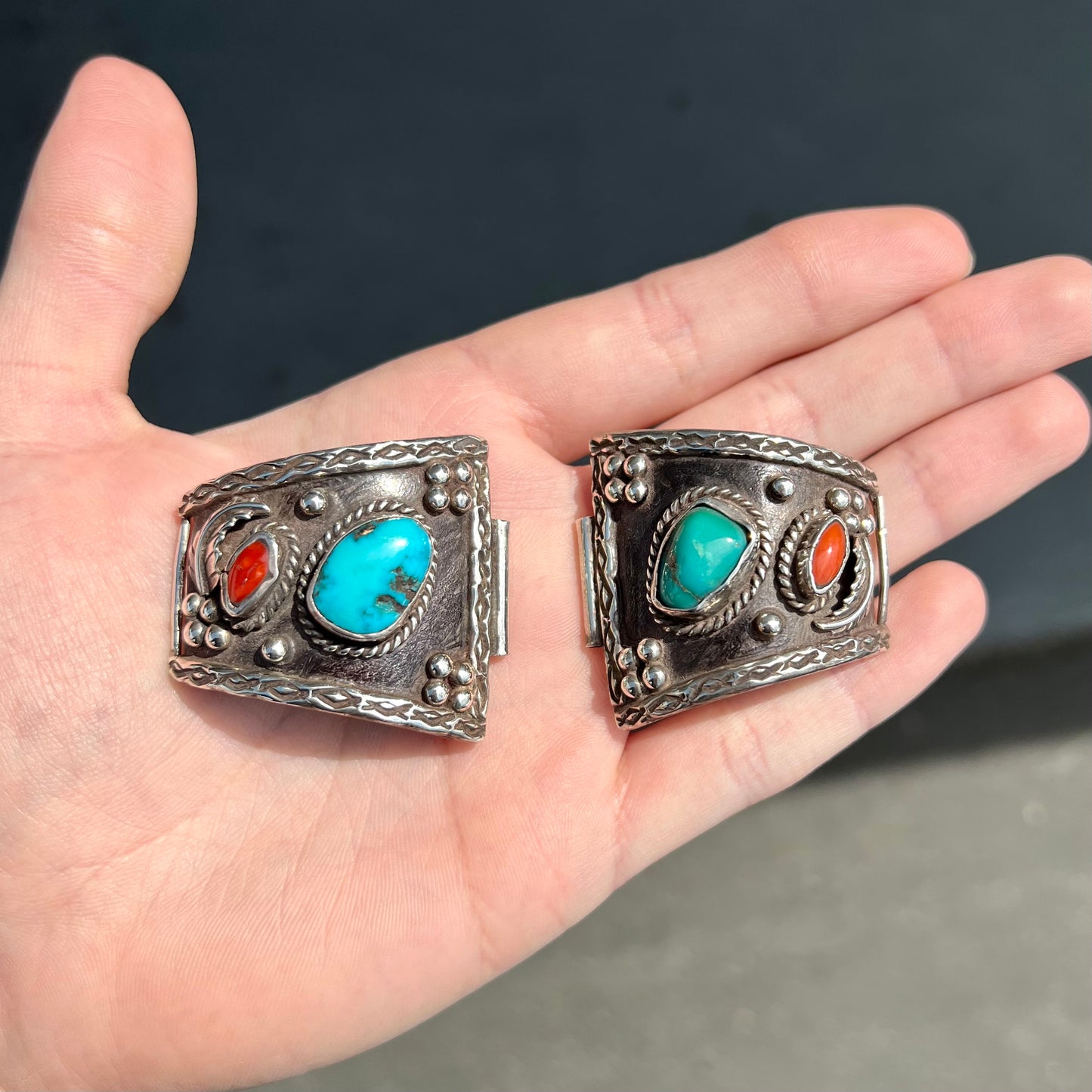 A pair of Navajo made sterling silver watch cuffs set with turquoise and coral stones.
