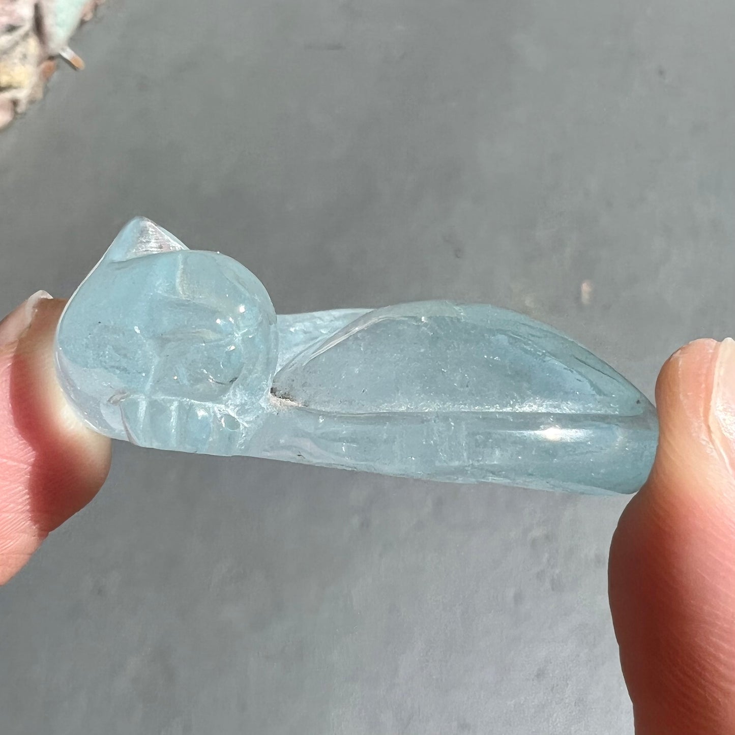 A stone cat carved from a sky blue topaz crystal.