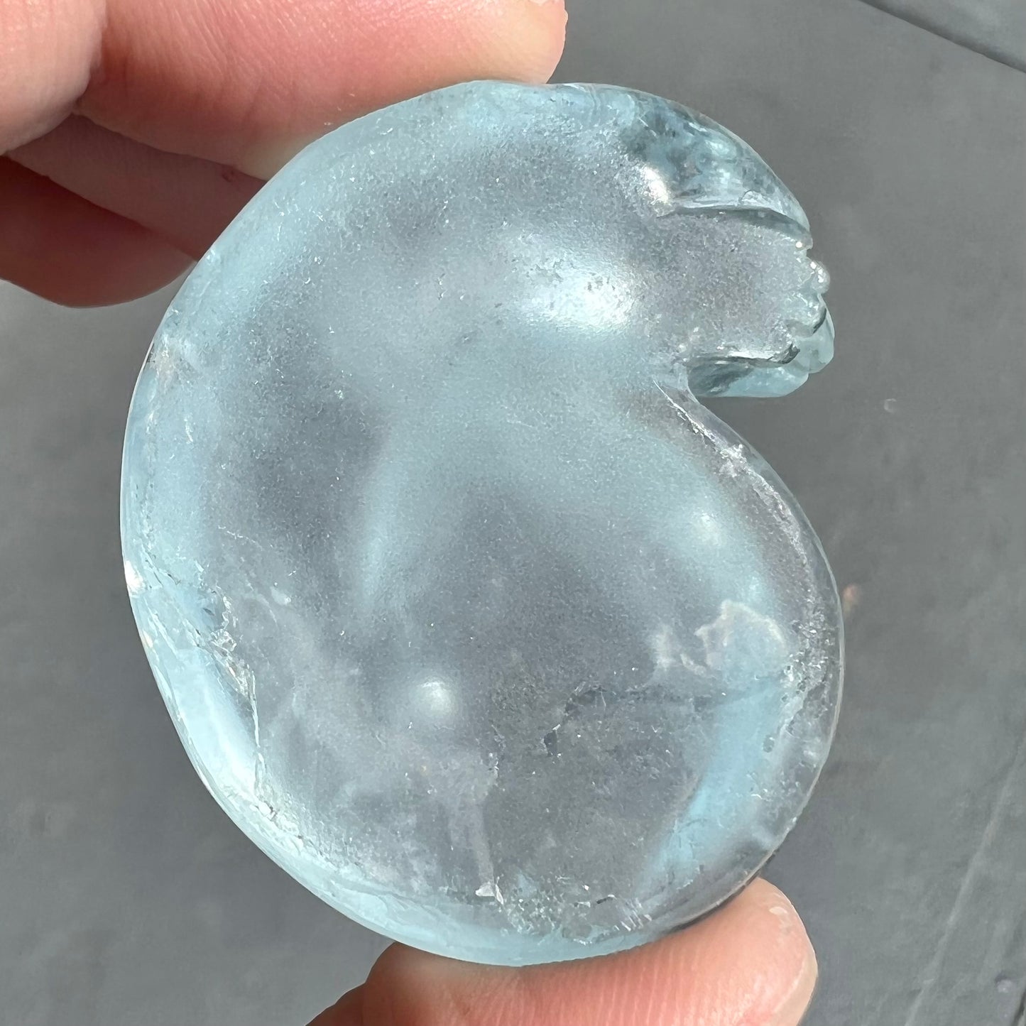 A stone cat carved from a sky blue topaz crystal.