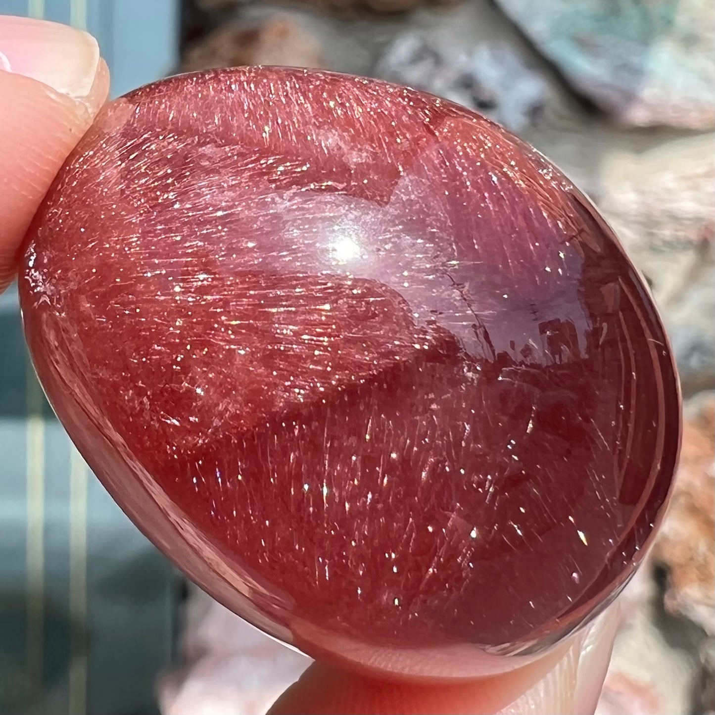 A large, oval cabochon cut strawberry quartz. The stone has a trapiche star-like pattern.