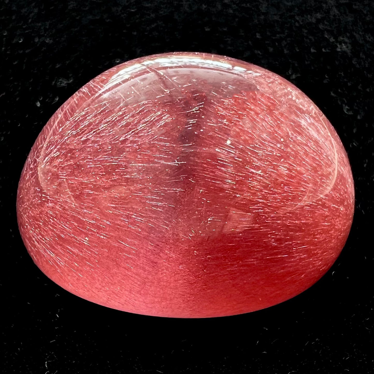 A large, oval cabochon cut strawberry quartz. The stone has a trapiche star-like pattern.