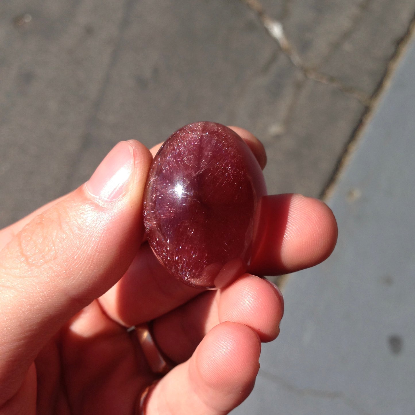 A large, oval cabochon cut strawberry quartz. The stone has a trapiche star-like pattern.