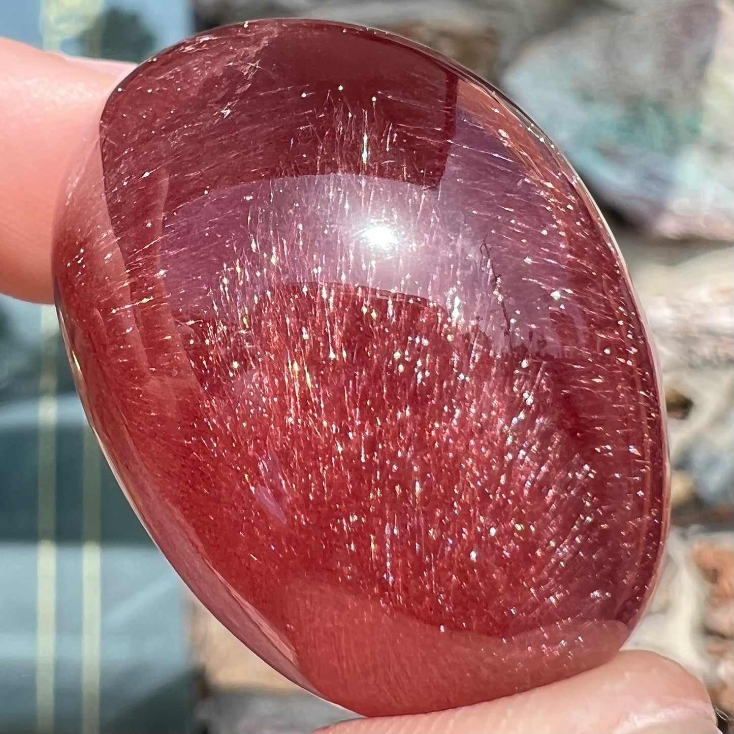 A large, oval cabochon cut strawberry quartz. The stone has a trapiche star-like pattern.