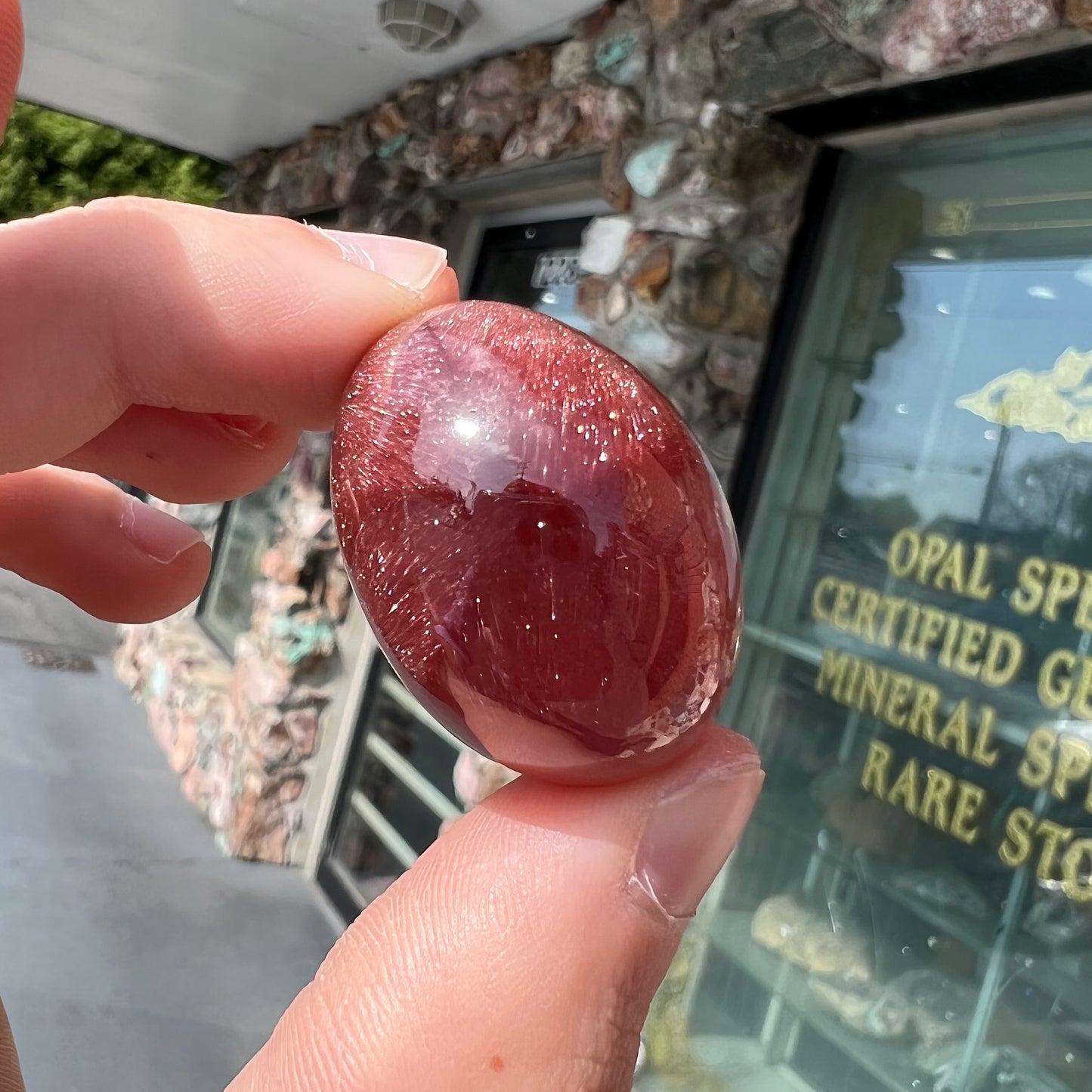 A large, oval cabochon cut strawberry quartz. The stone has a trapiche star-like pattern.