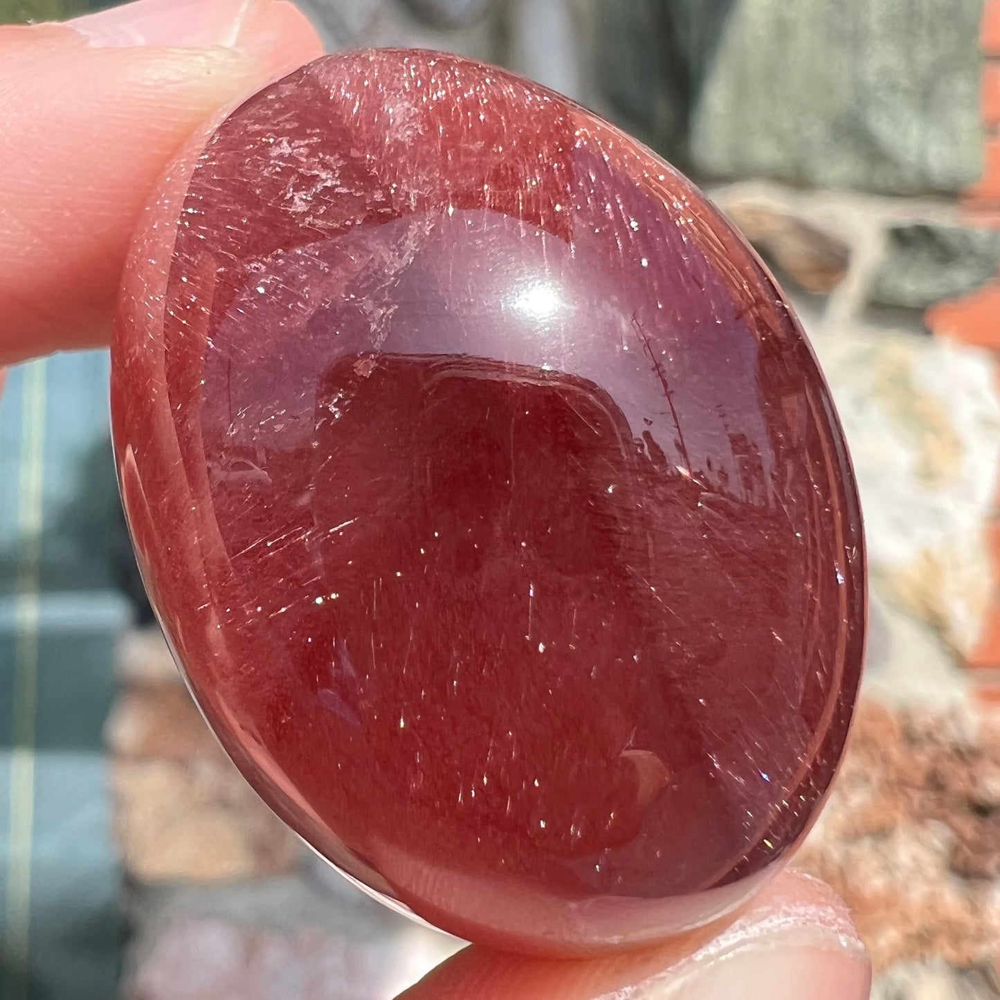 A large, oval cabochon cut strawberry quartz. The stone has a trapiche star-like pattern.