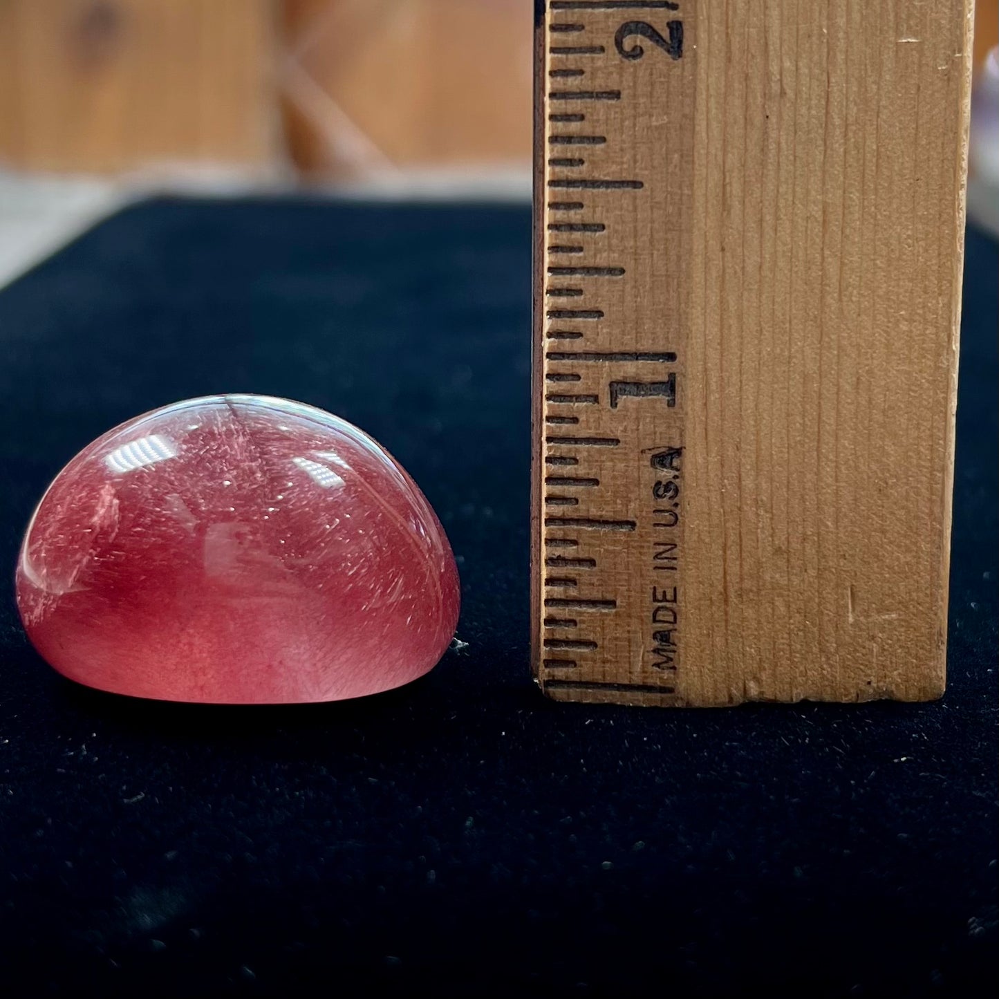 A large, oval cabochon cut strawberry quartz. The stone has a trapiche star-like pattern.