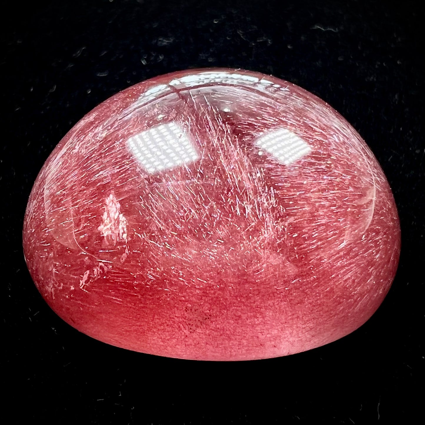 A large, oval cabochon cut strawberry quartz. The stone has a trapiche star-like pattern.