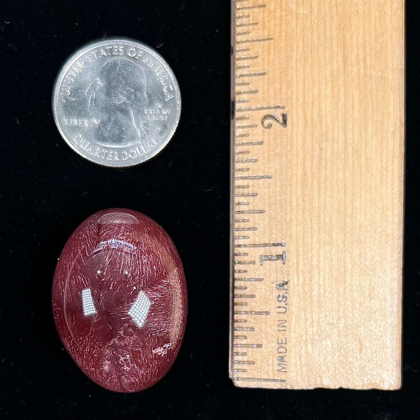 A large, oval cabochon cut strawberry quartz. The stone has a trapiche star-like pattern.