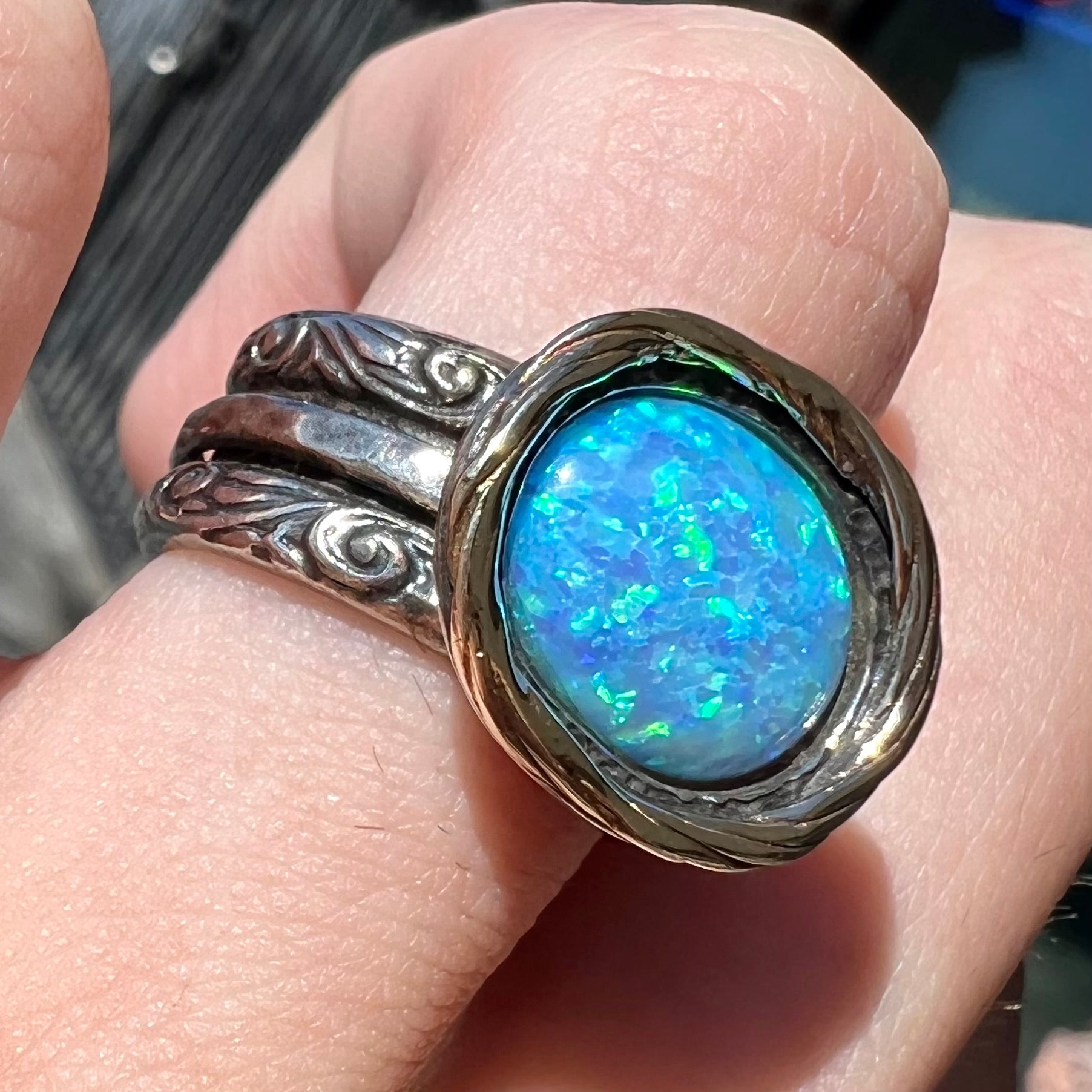 A filigree etched two tone silver and gold spinner ring set with a lab created black opal.