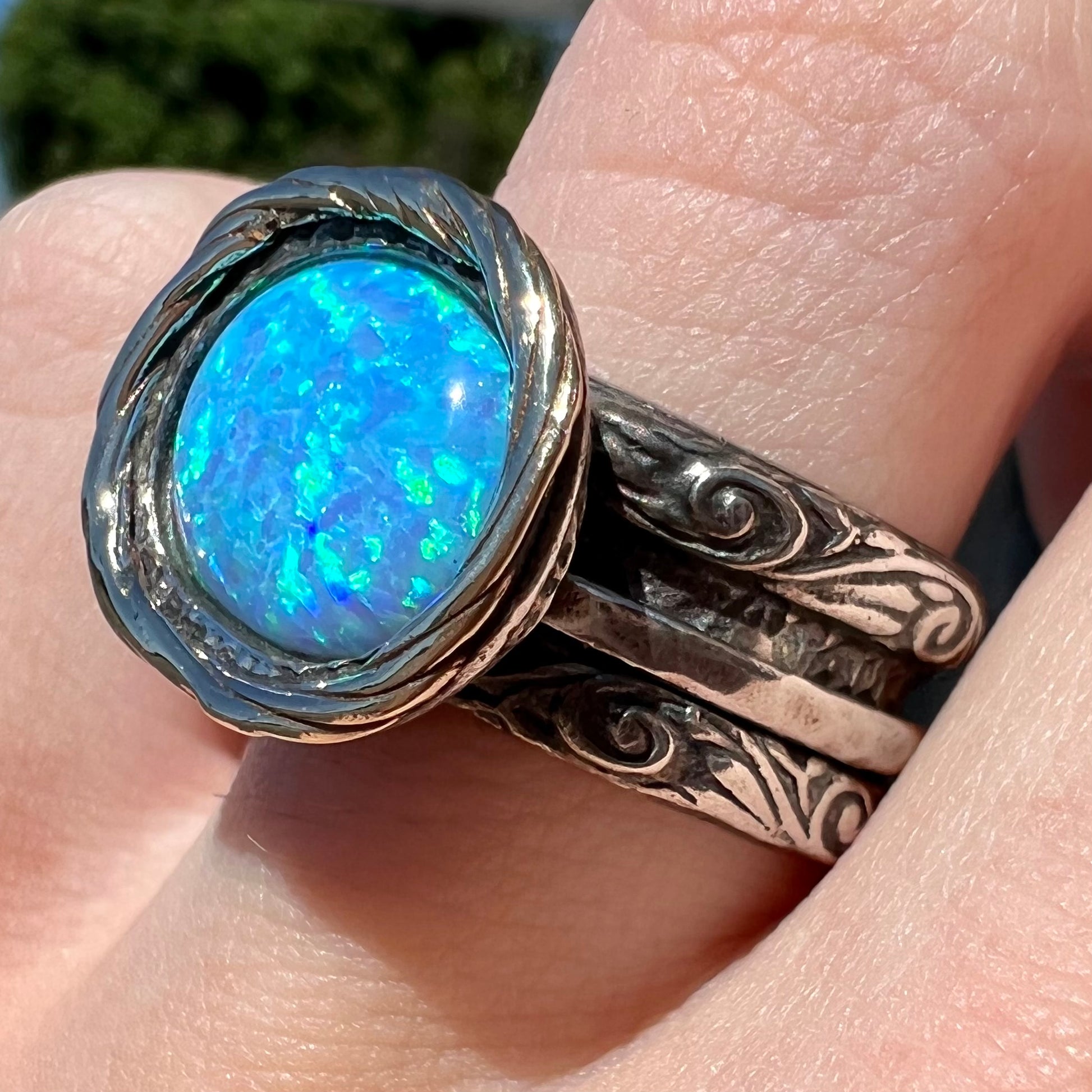 A filigree etched two tone silver and gold spinner ring set with a lab created black opal.