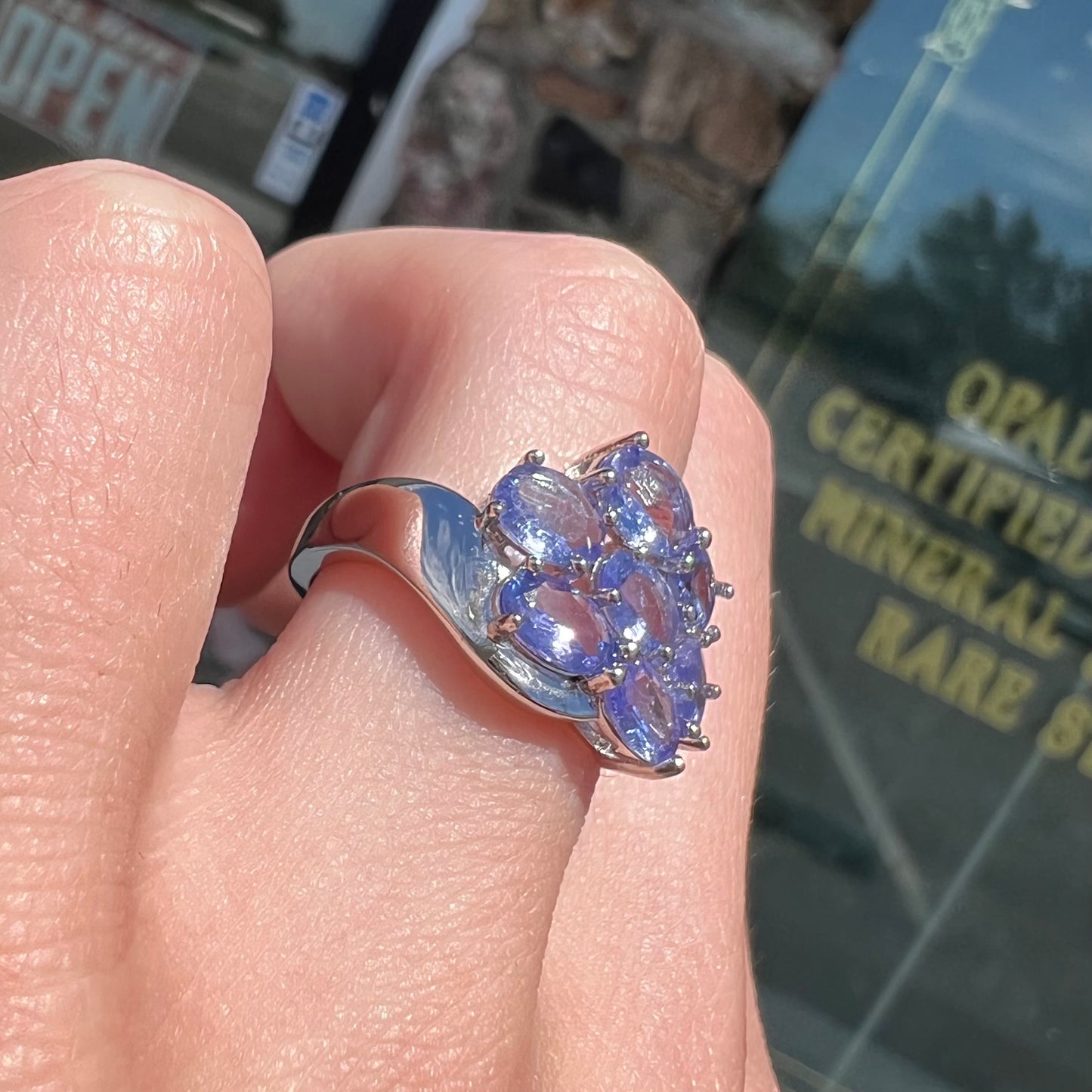 A sterling silver cluster ring prong set with seven faceted oval cut blue tanzanite stones.