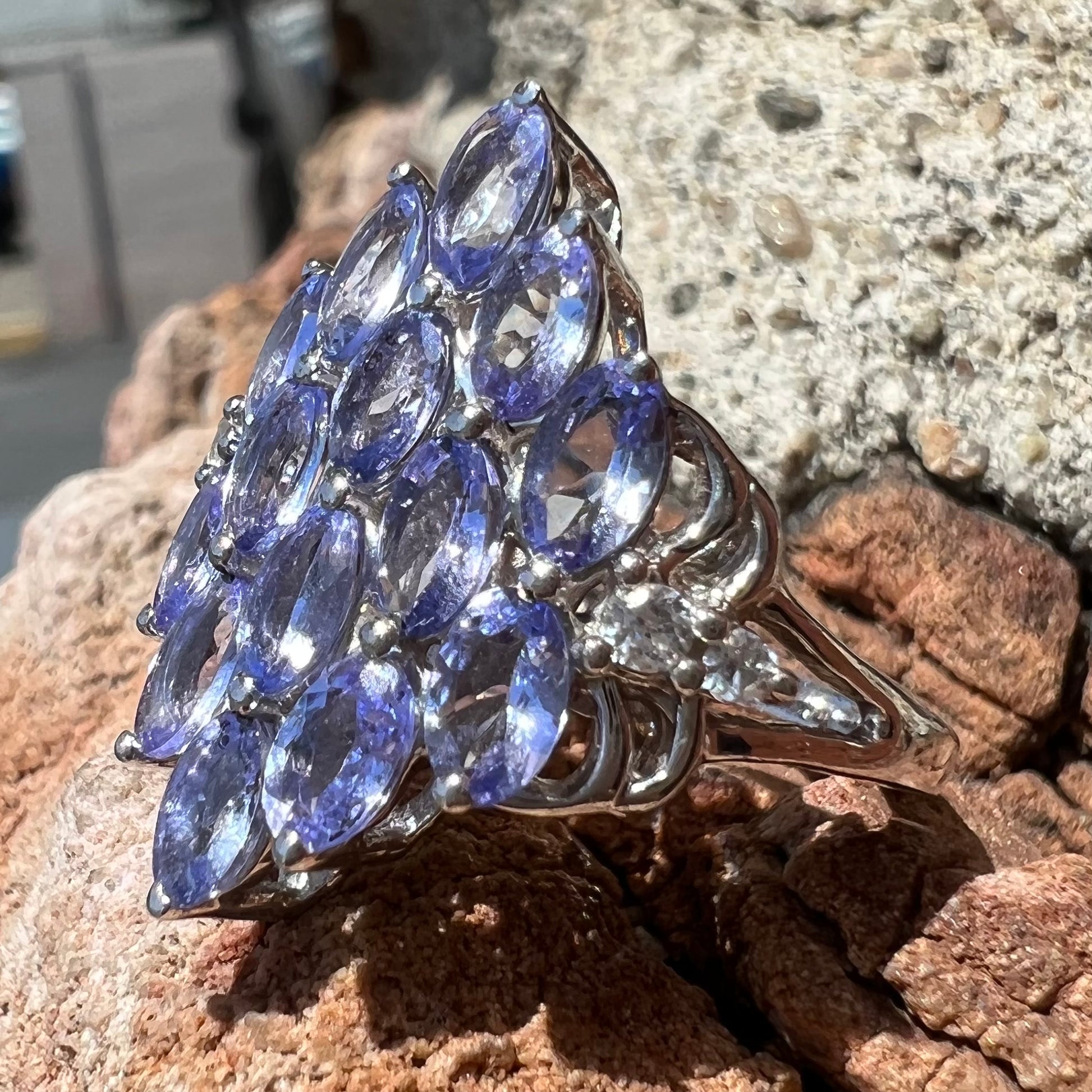 A sterling silver gemstone cluster ring set with oval cut tanzanite stones and round cubic zirconia accents.