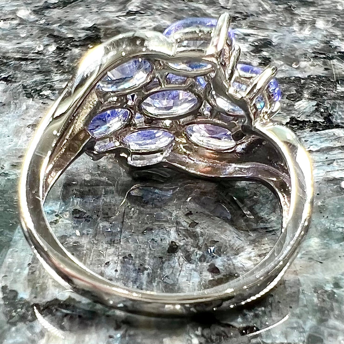 A sterling silver cluster ring prong set with seven faceted oval cut blue tanzanite stones.