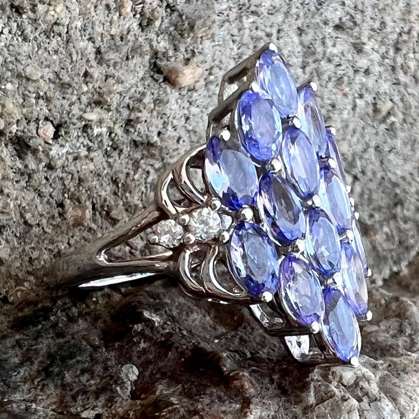 A sterling silver gemstone cluster ring set with oval cut tanzanite stones and round cubic zirconia accents.