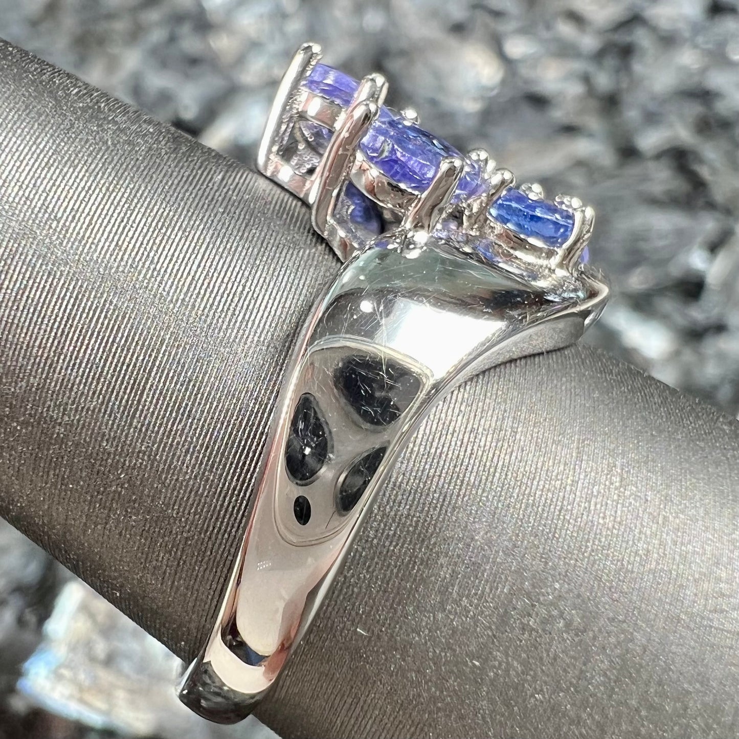 A sterling silver cluster ring prong set with seven faceted oval cut blue tanzanite stones.