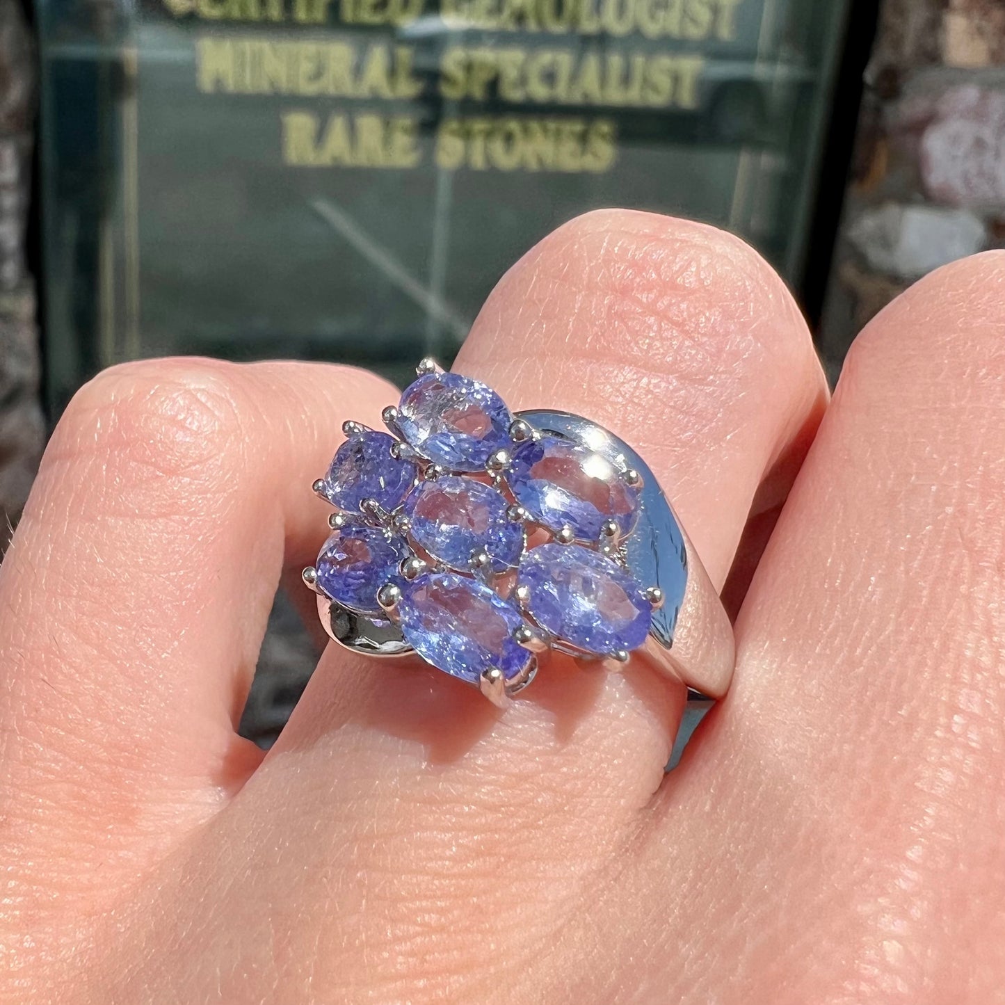 A sterling silver cluster ring prong set with seven faceted oval cut blue tanzanite stones.