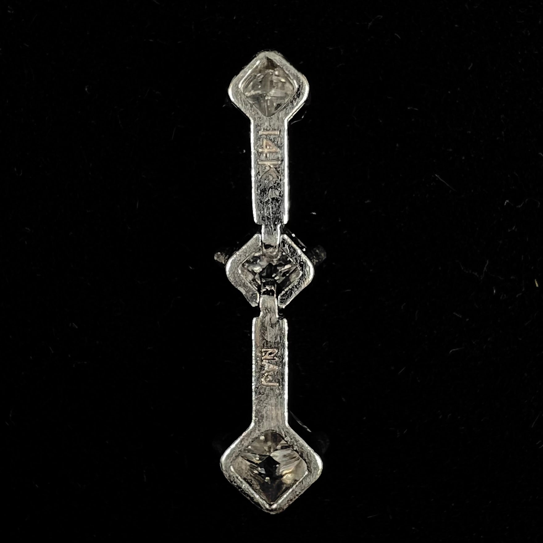 A ladies' white gold three stone drop pendant set with princess cut diamonds.  There are two points of articulation.