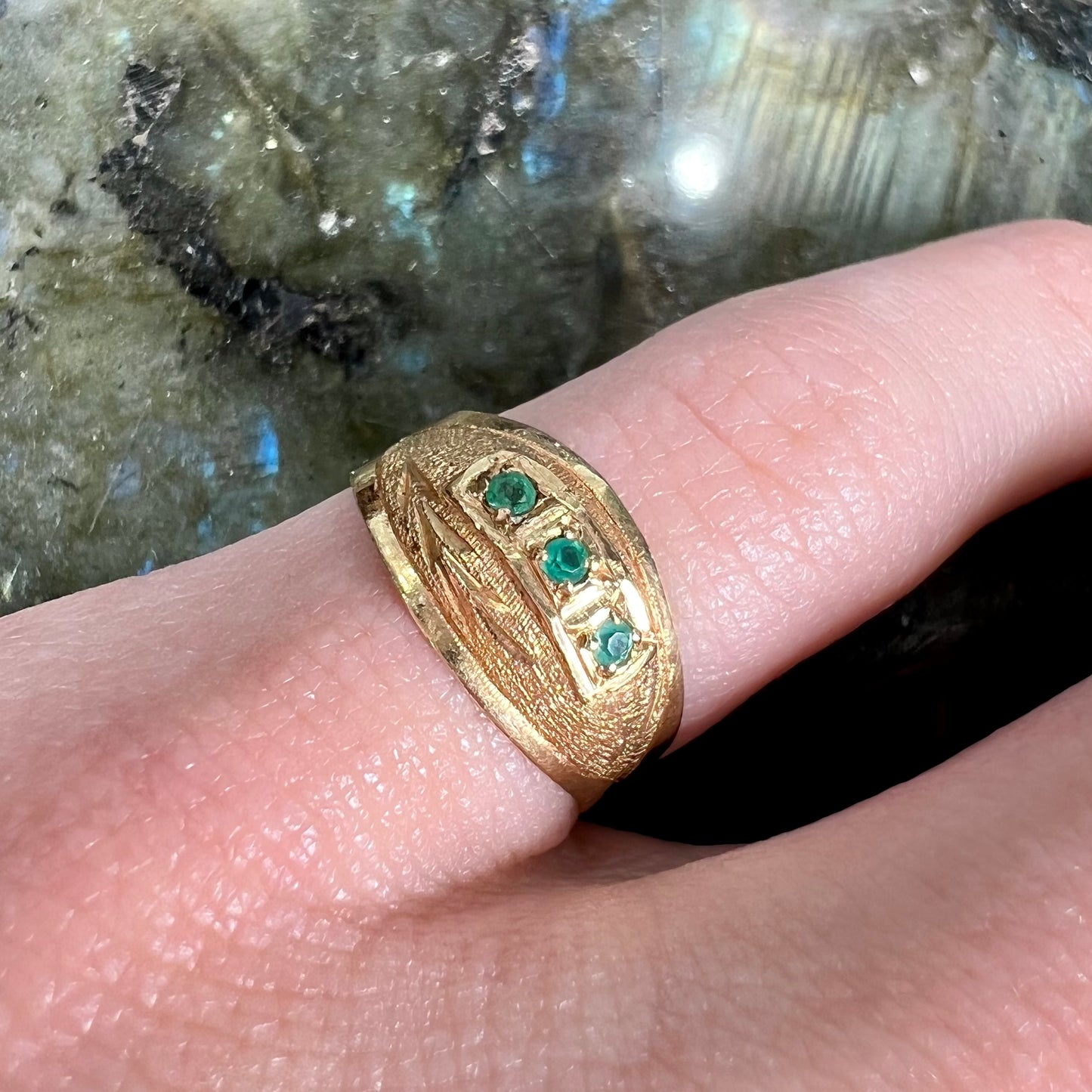 A 1920's style yellow gold three stone round cut emerald ring.