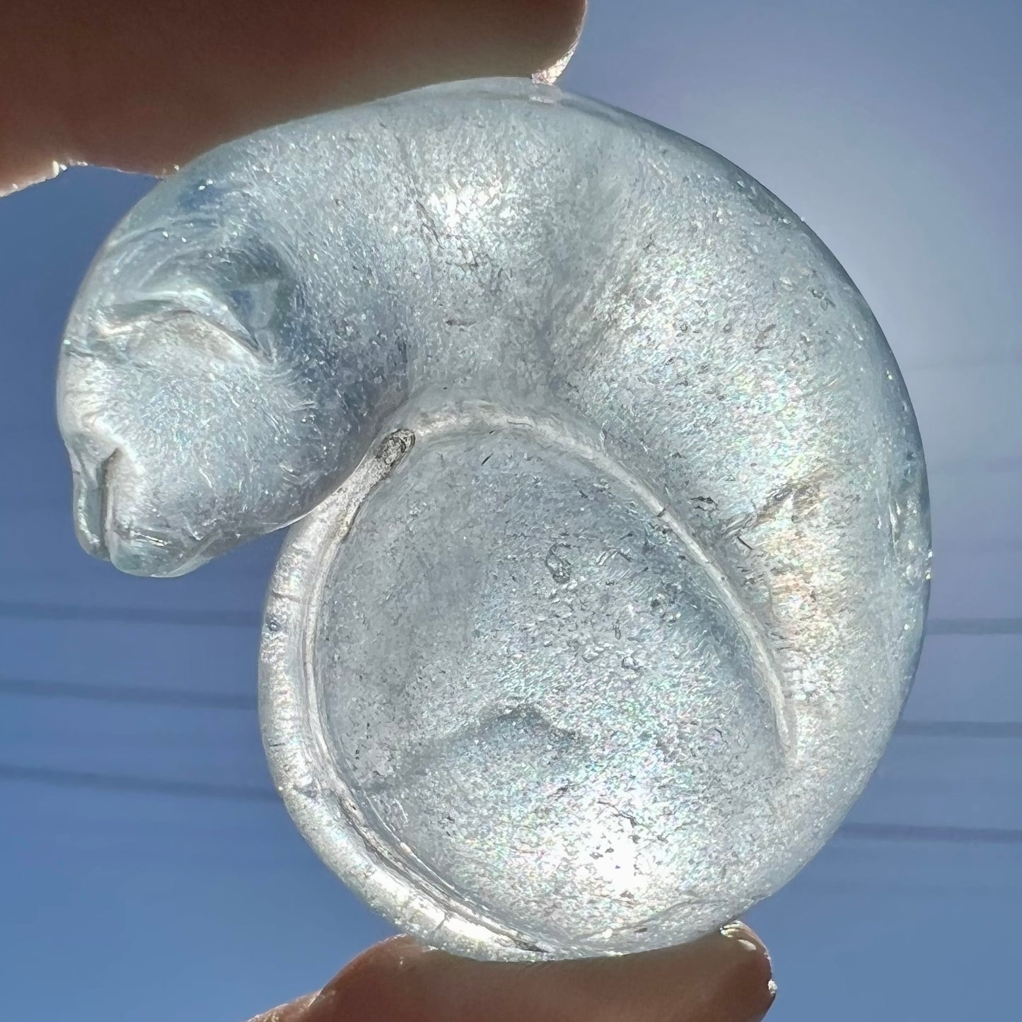 A stone cat carved from a sky blue topaz crystal.