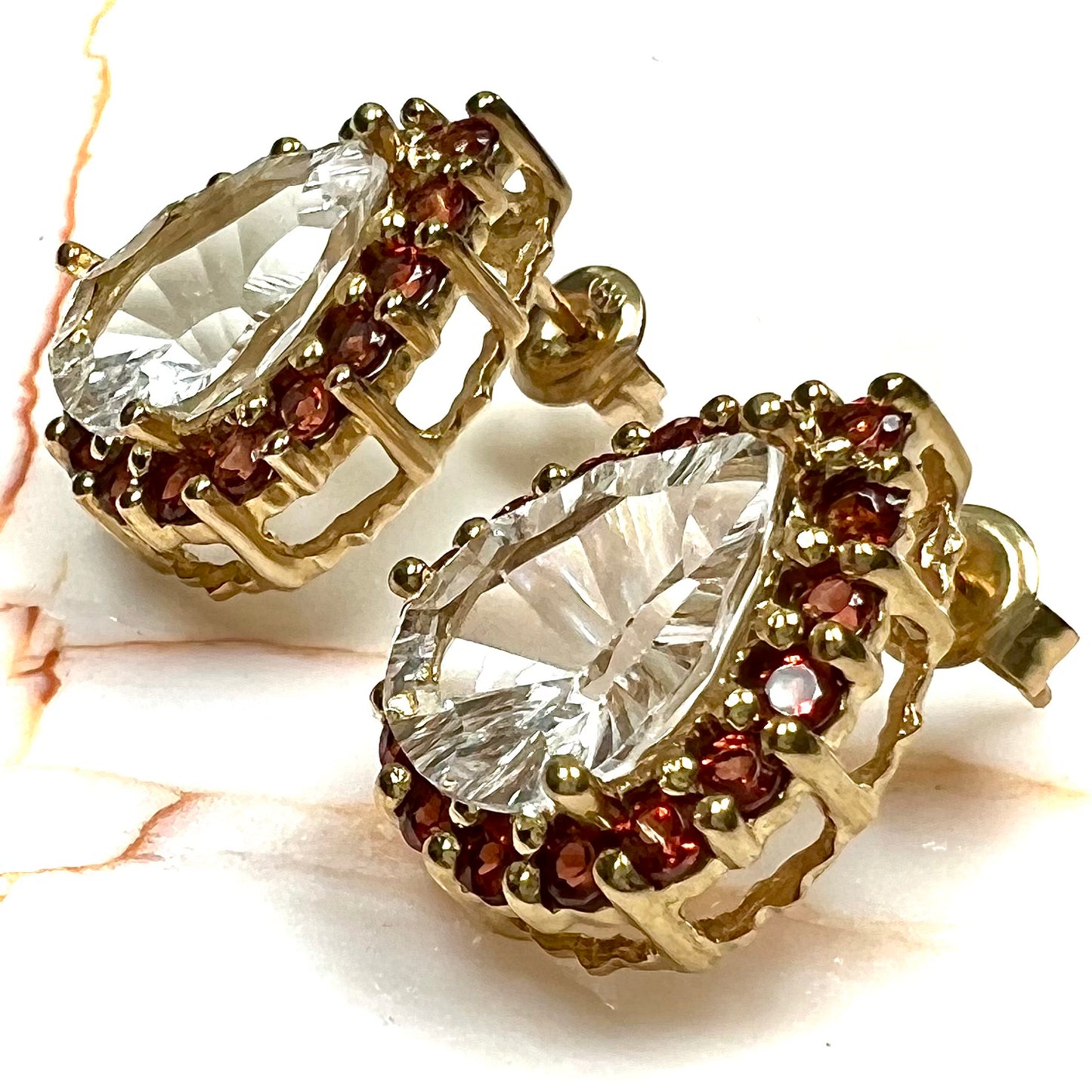 Pear shape white topaz and garnet halo stud earrings in yellow gold.