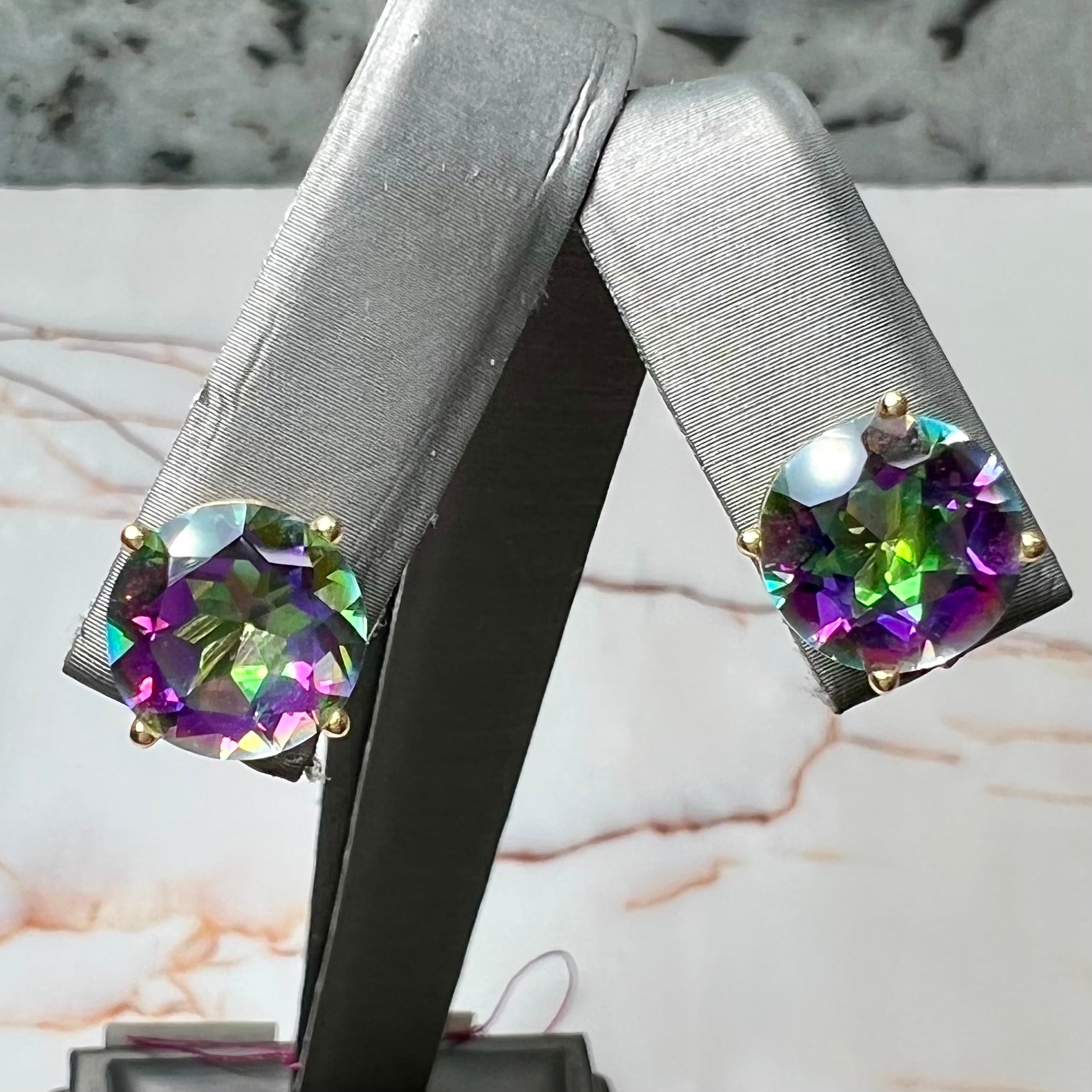 Round cut mystic topaz stones set in yellow gold prong-set push-back earrings.