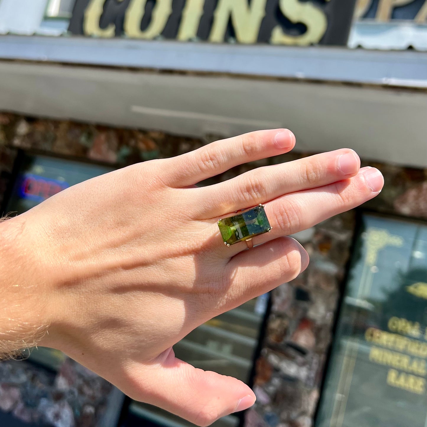 A faceted step-cut dark green tourmaline basket set solitaire ring cast in yellow gold.