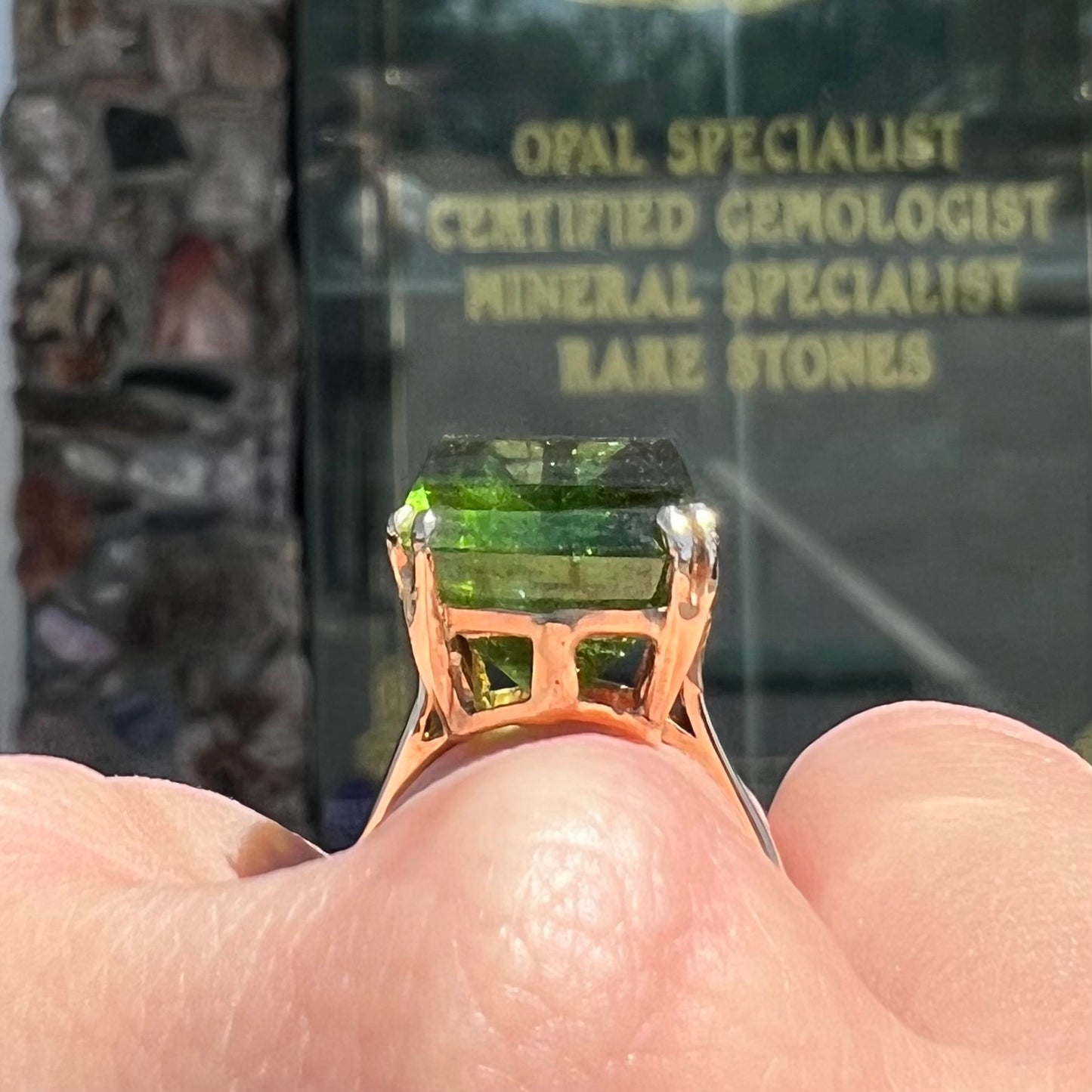 A faceted step-cut dark green tourmaline basket set solitaire ring cast in yellow gold.