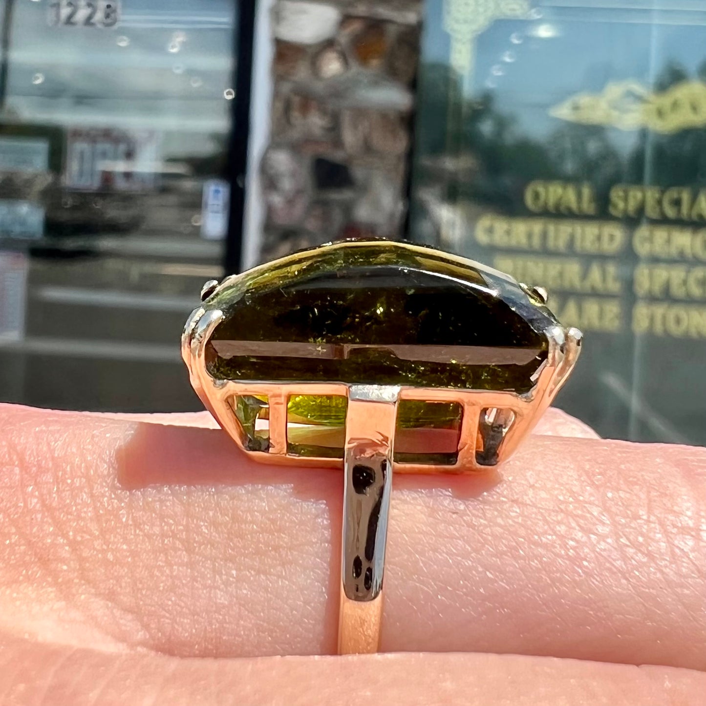 A faceted step-cut dark green tourmaline basket set solitaire ring cast in yellow gold.