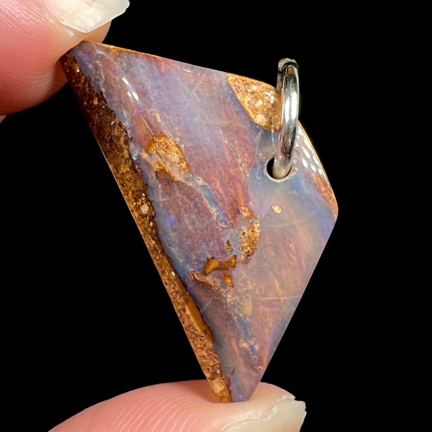 A drilled boulder opal stone with a sterling silver ring through the hole to be worn as a pendant.