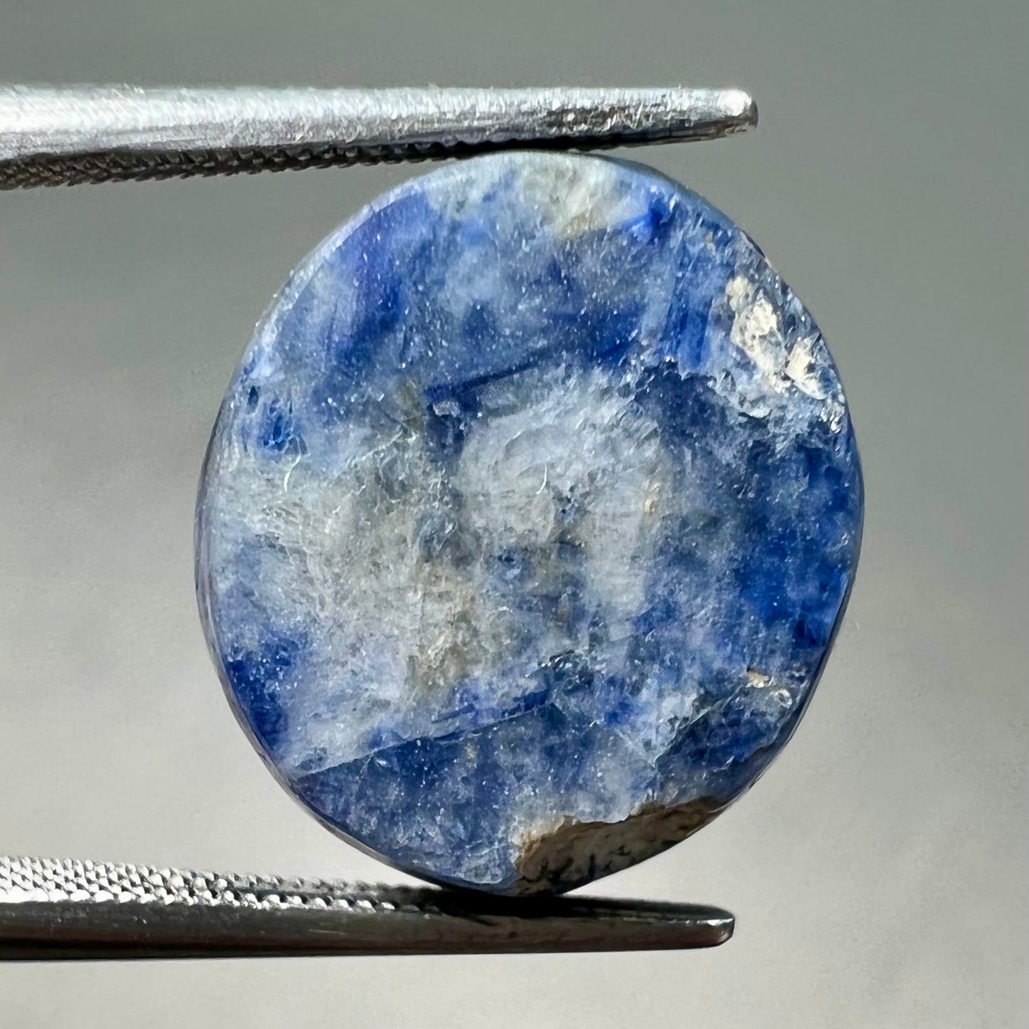 A loose, oval cabochon cut blue trapiche star sapphire stone.